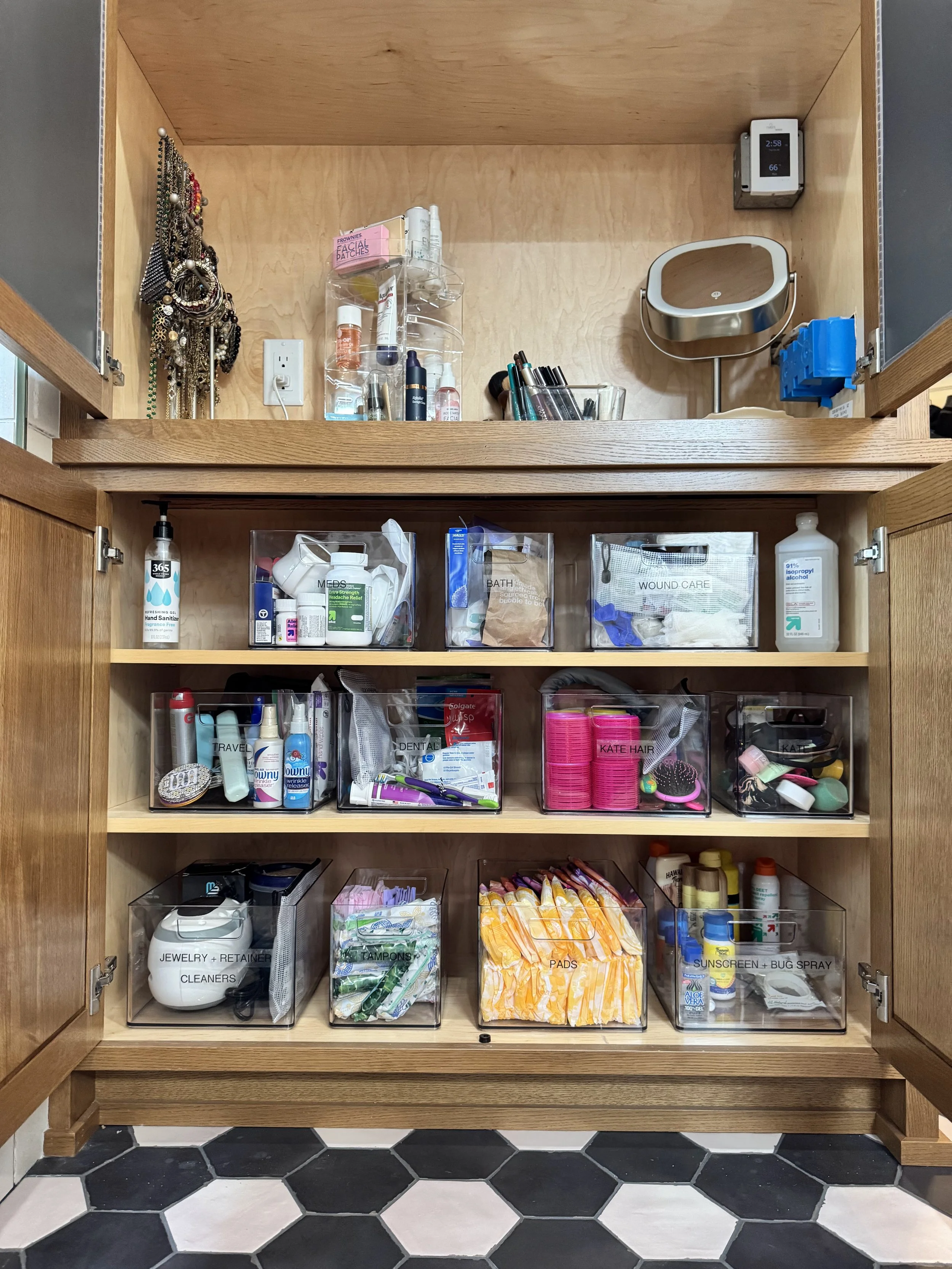 Hexagonal tile flooring with an open cabinet showing organized items inside of clear containers