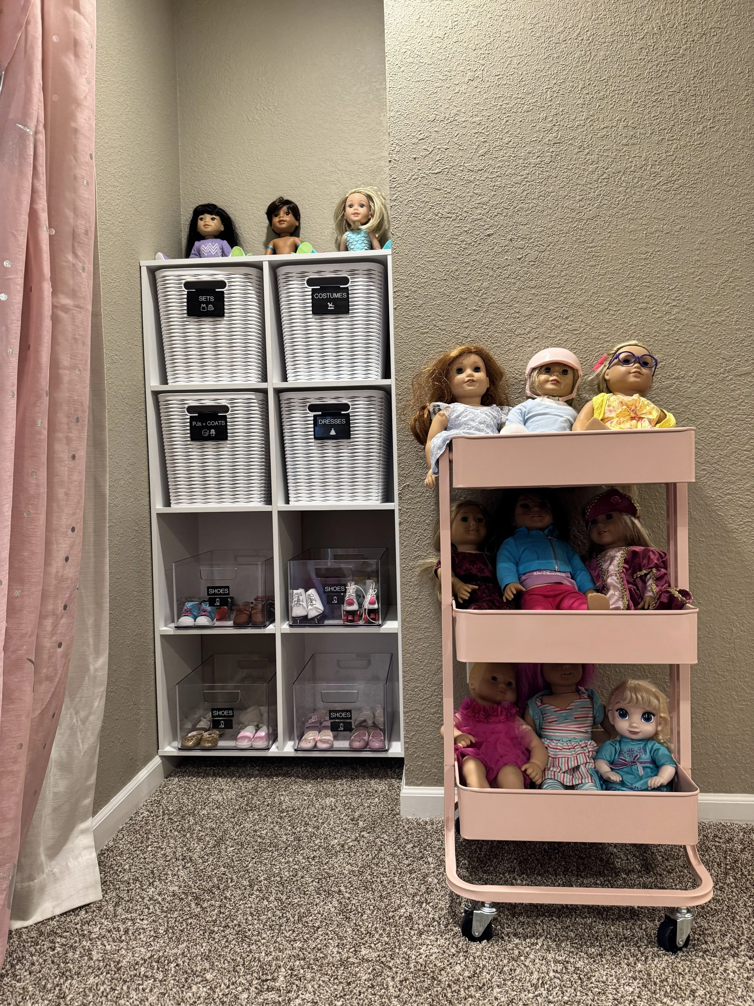White shelves and a pink rolling cart organizing toy dolls