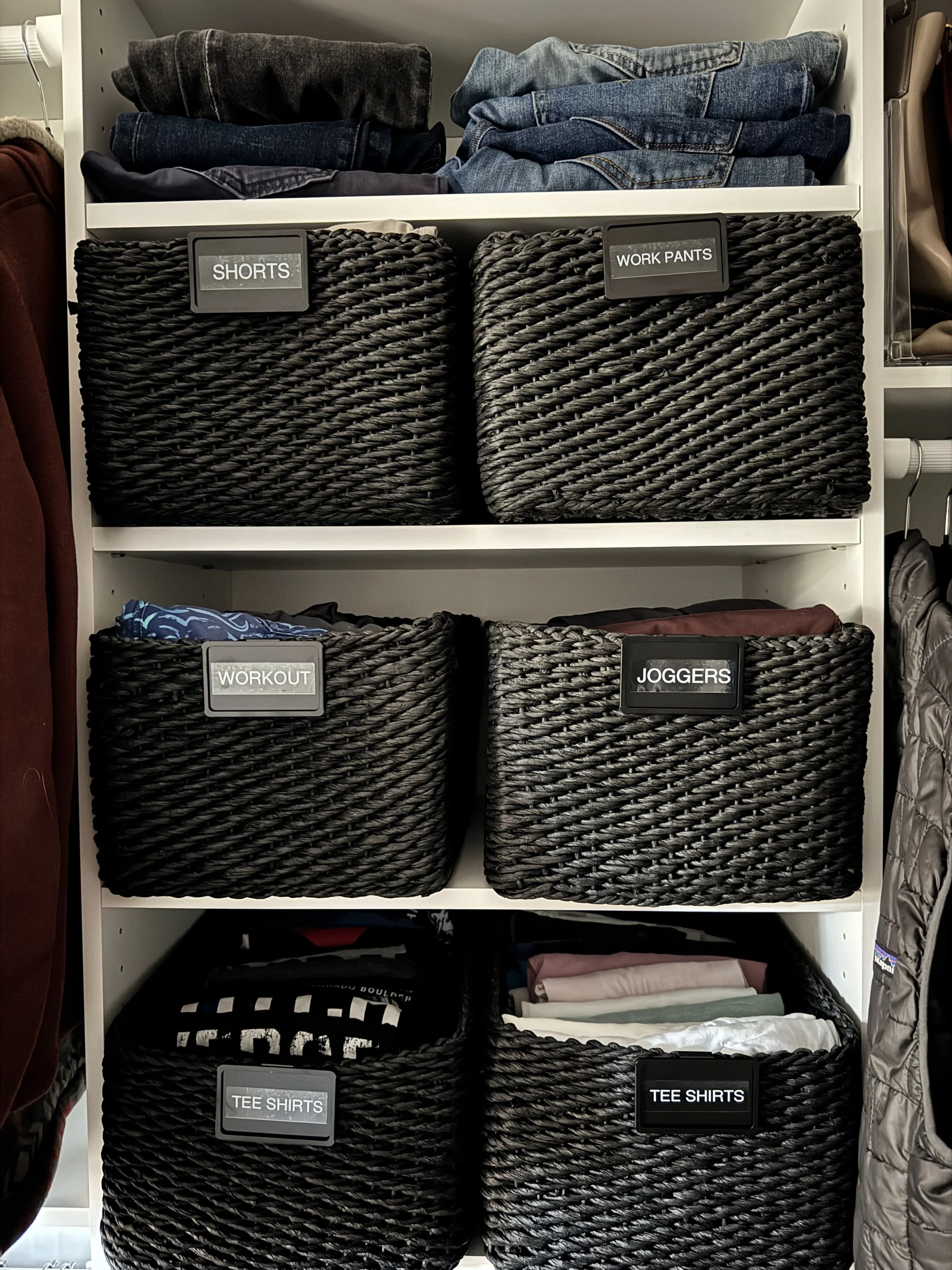 black woven baskets with black labels in a closet
