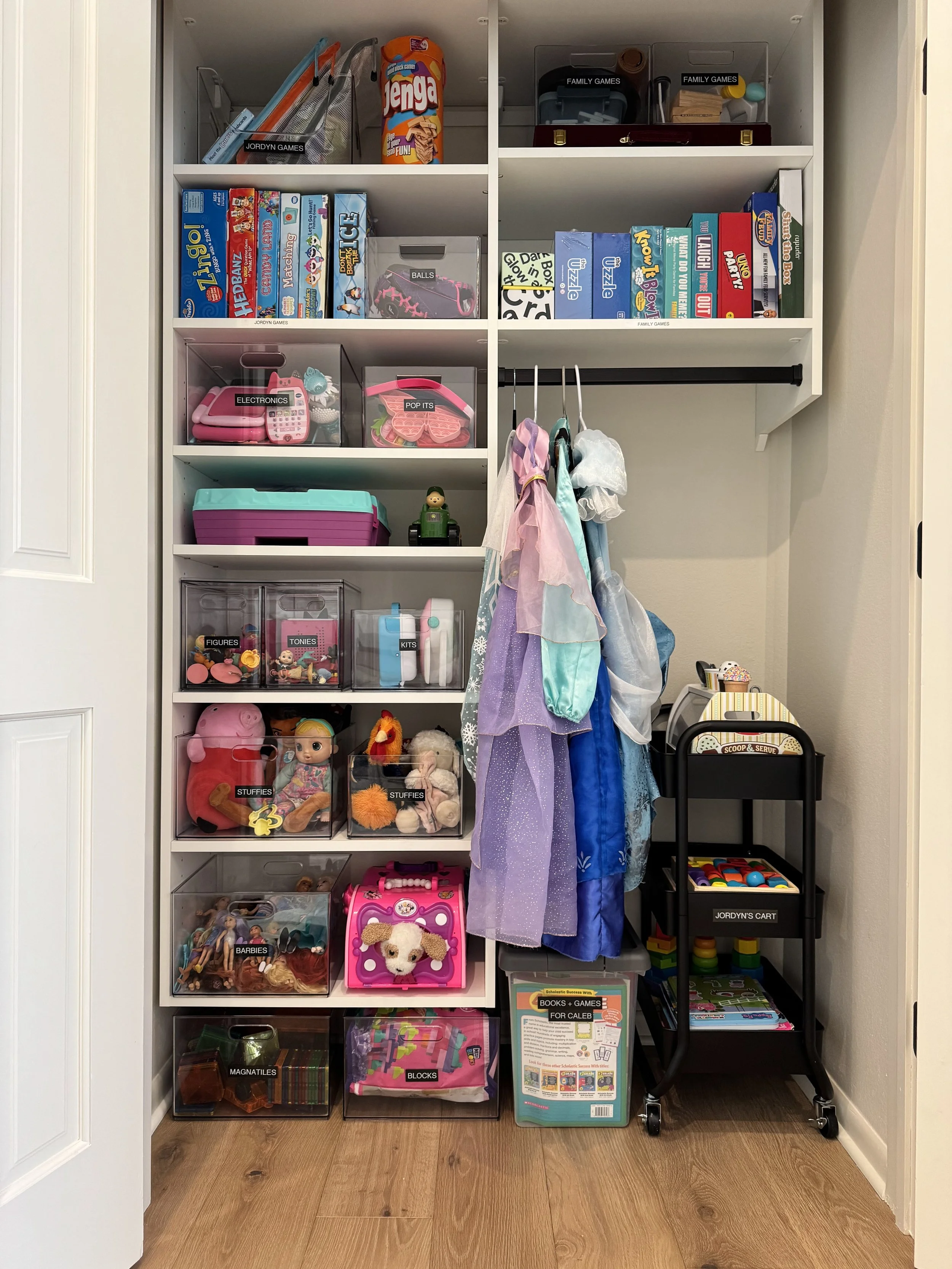 A toy closet with a rolling cart and brightly colored toys and games