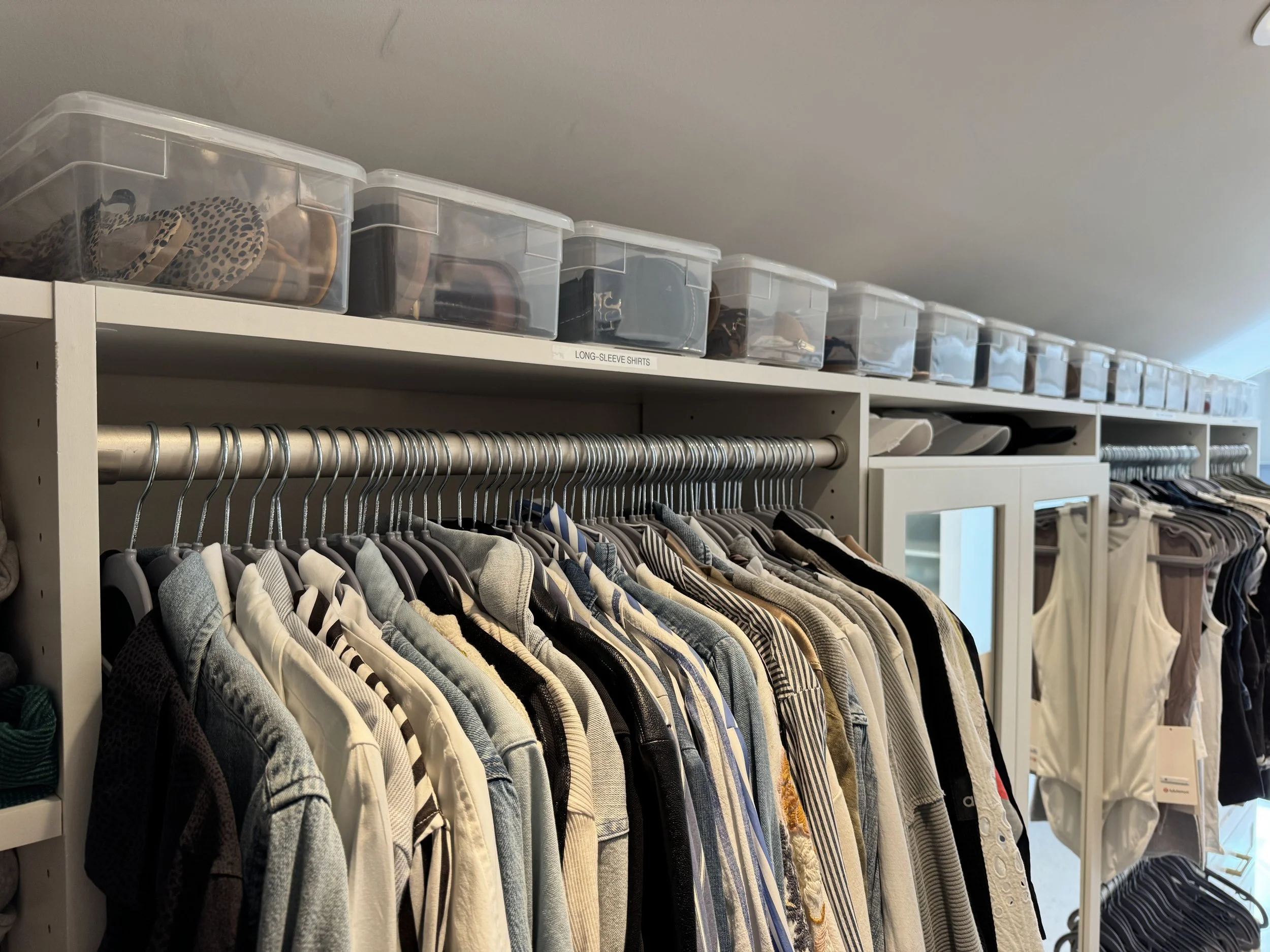 clear shoe boxes in a closet with hanging clothes on matching hangers