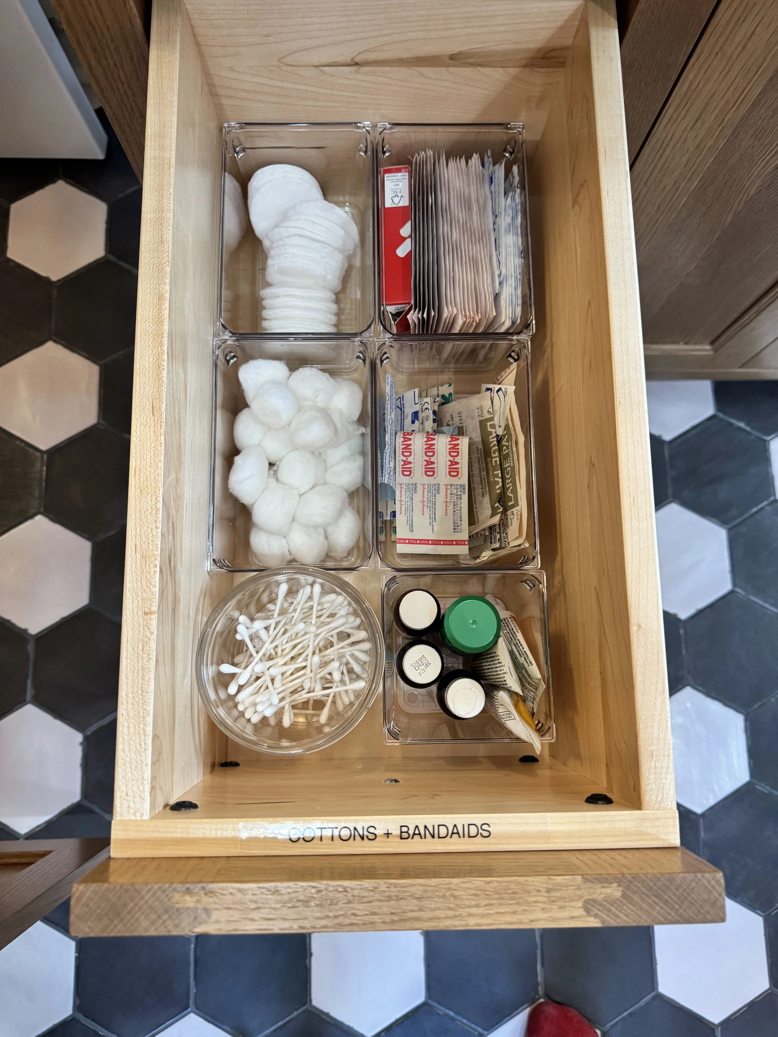 an open bathroom drawer with small containers organized with items
