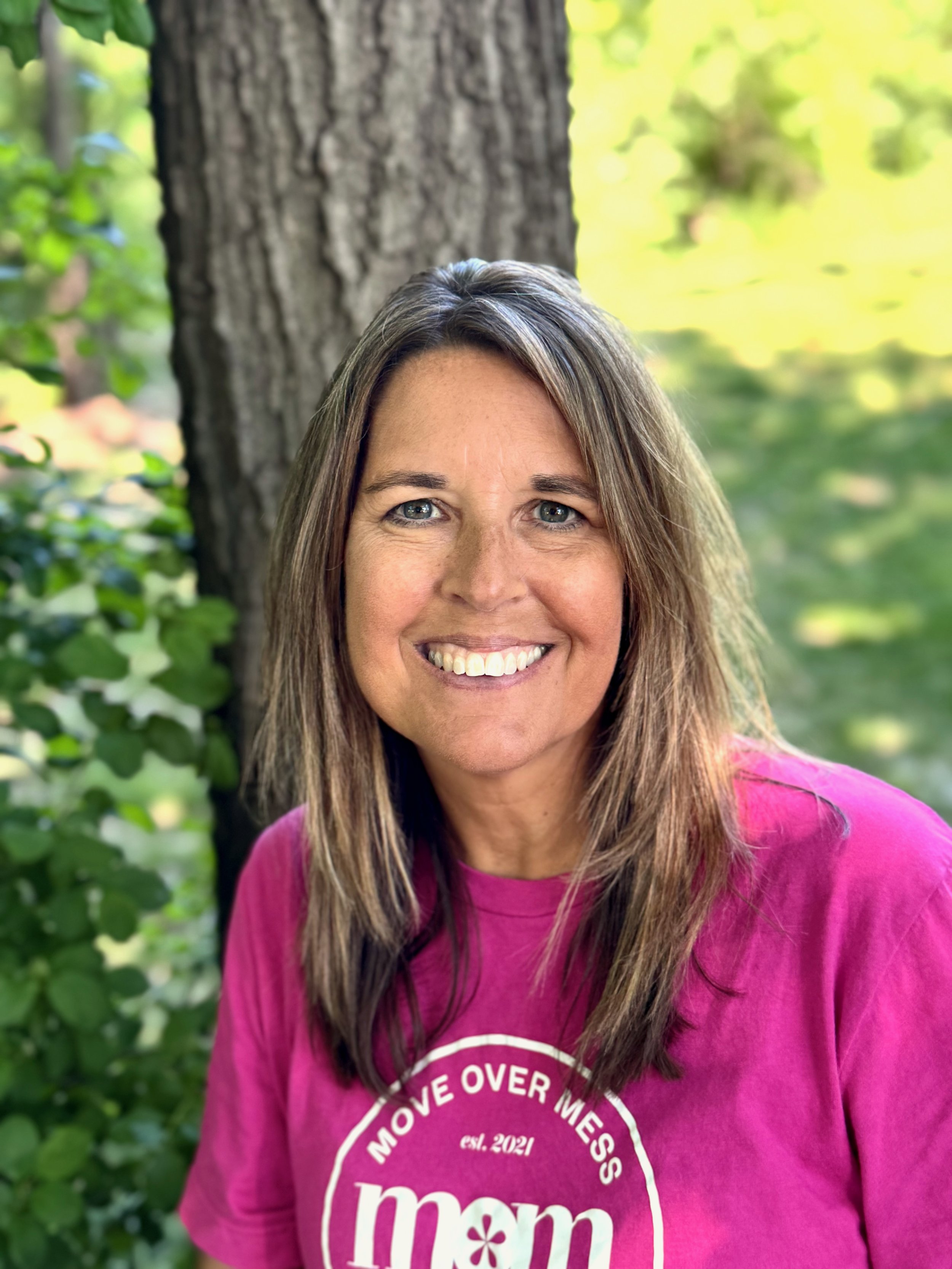 Organizer Jenni standing outside in a pink shirt in front of a tree