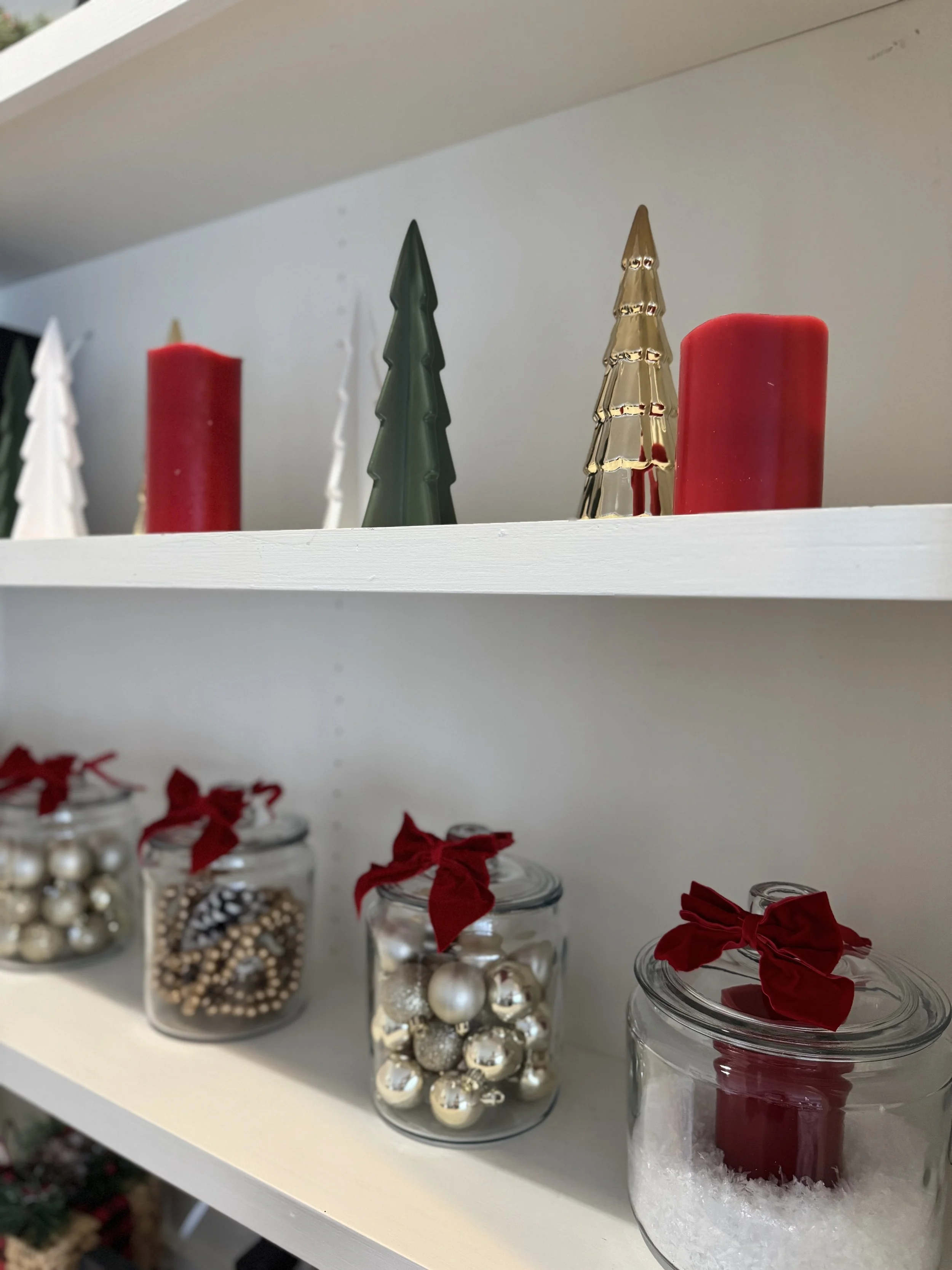 Red, green, and gold trees and candles on white shelves