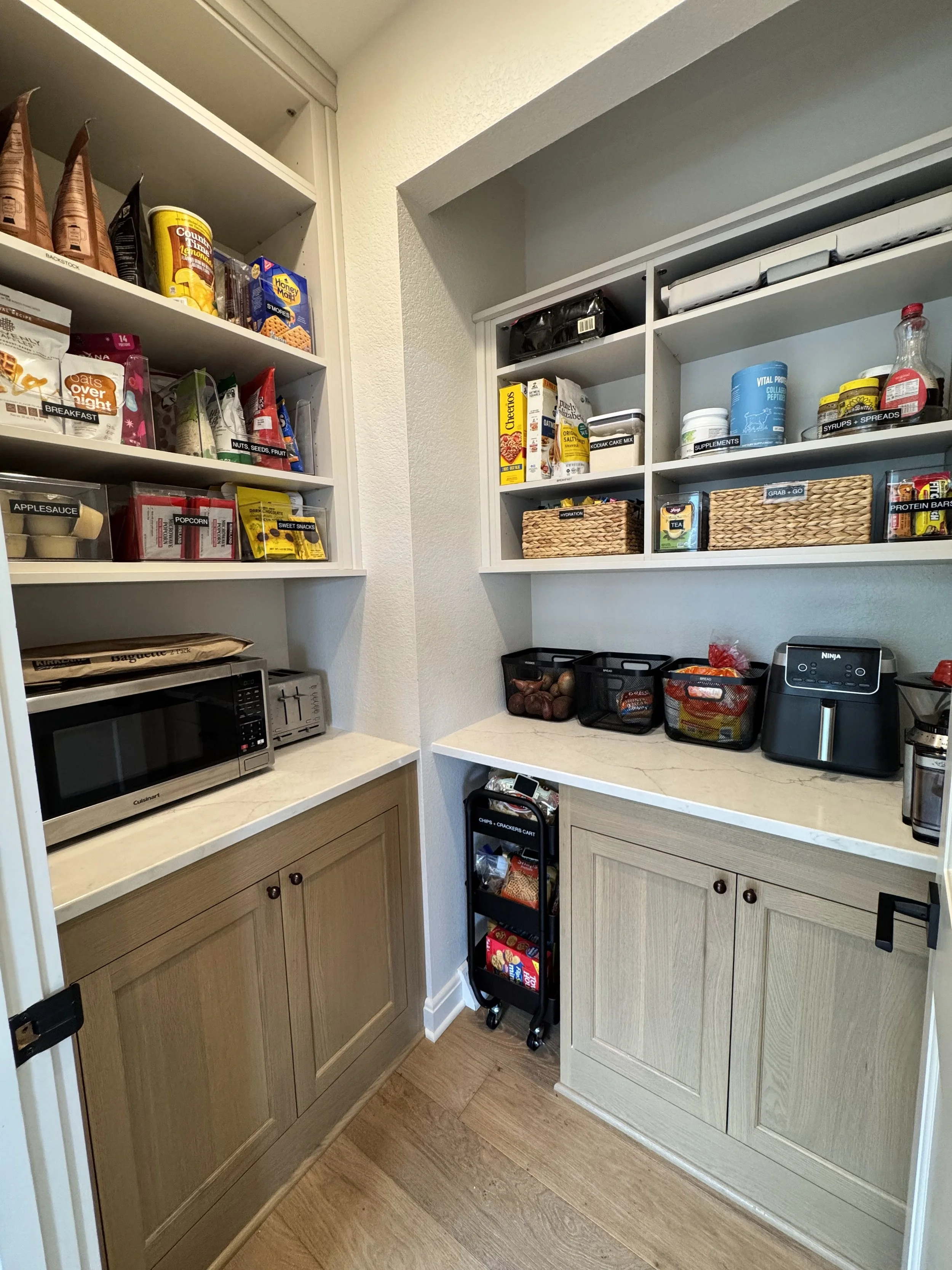 A pantry with woven baskets and black metal containers