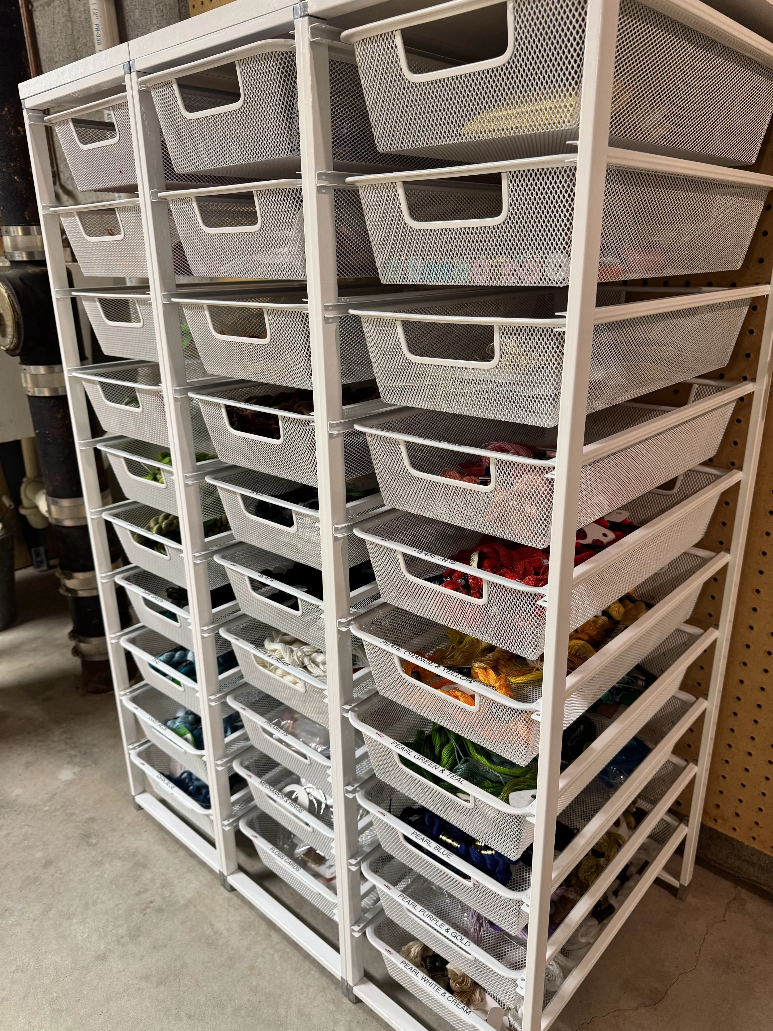 White metal drawers that are storing multiple types of sewing thread