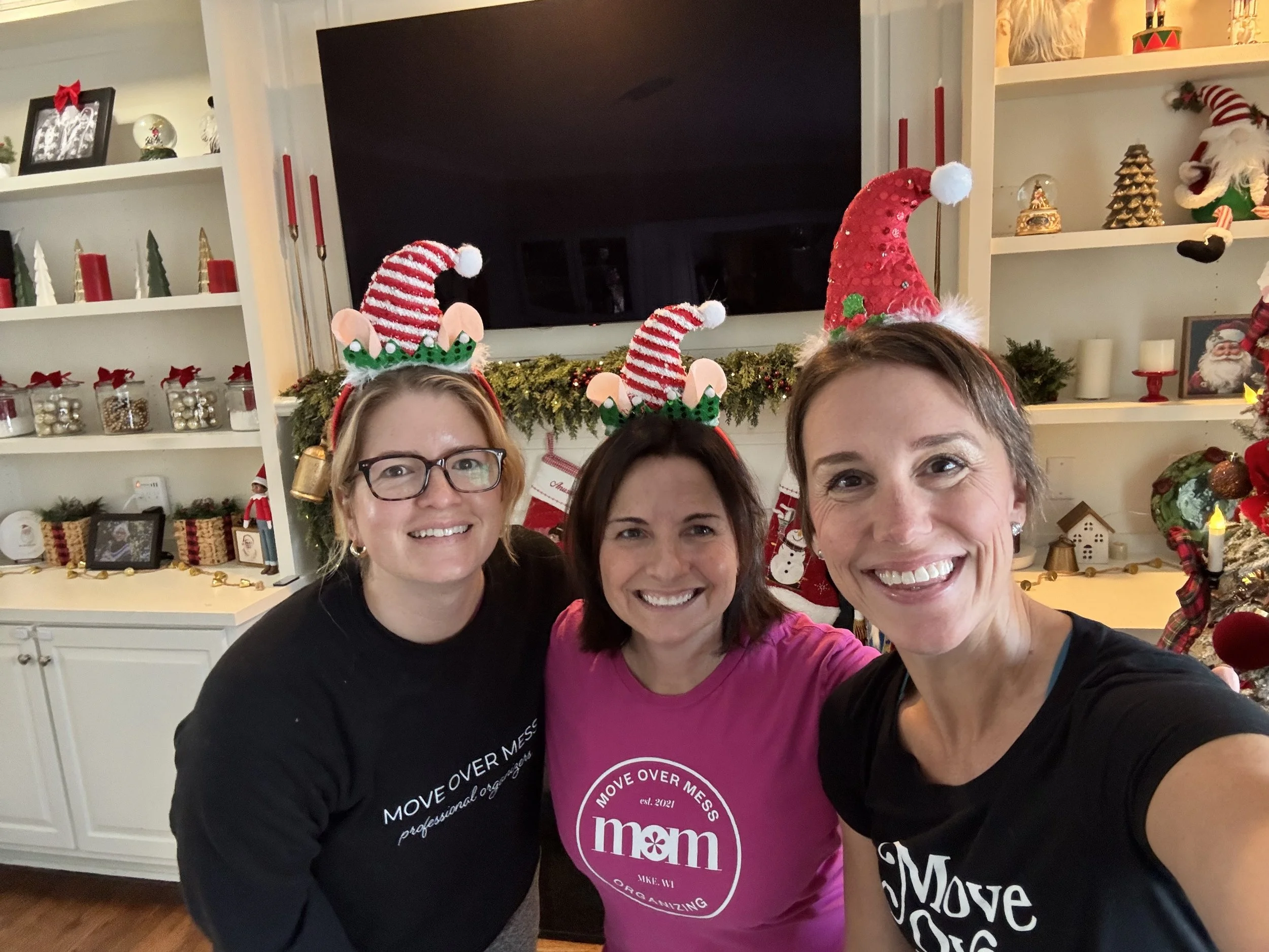 Three women smiling at the camera wearing festive Santa hats