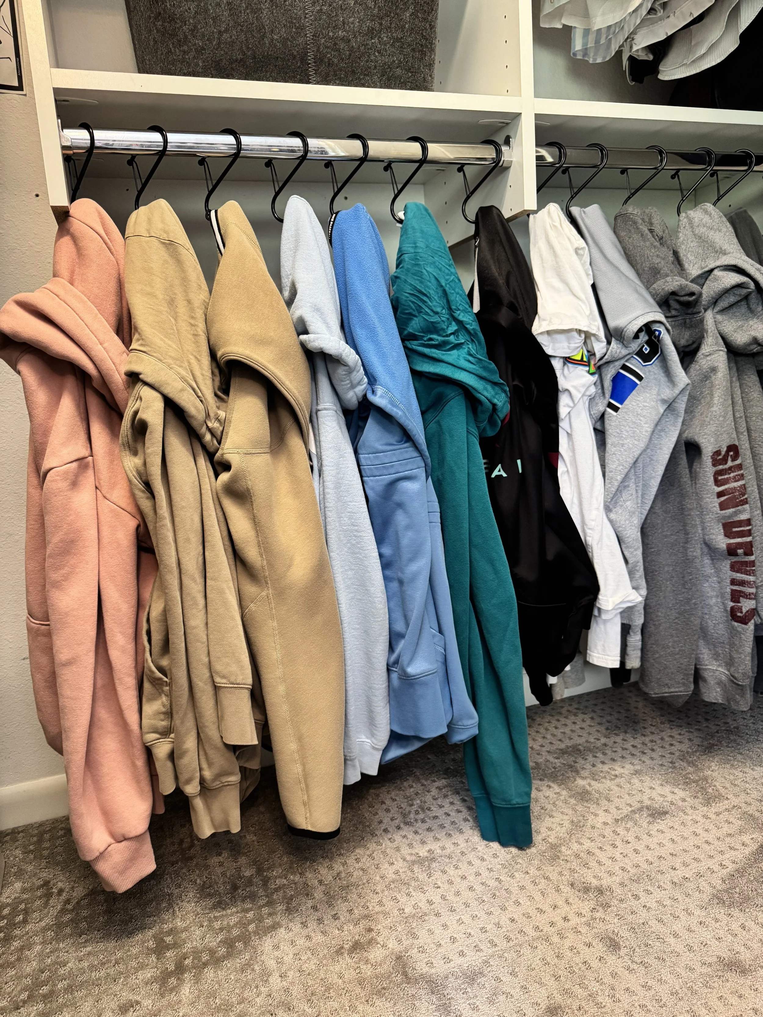 Hoodies organized by color in a kids' closet