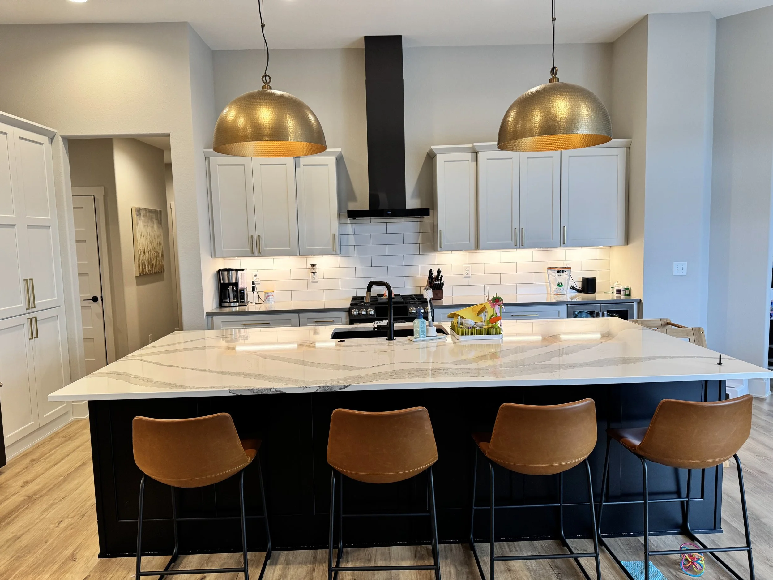clean kitchen with gold light fixtures and clear counters