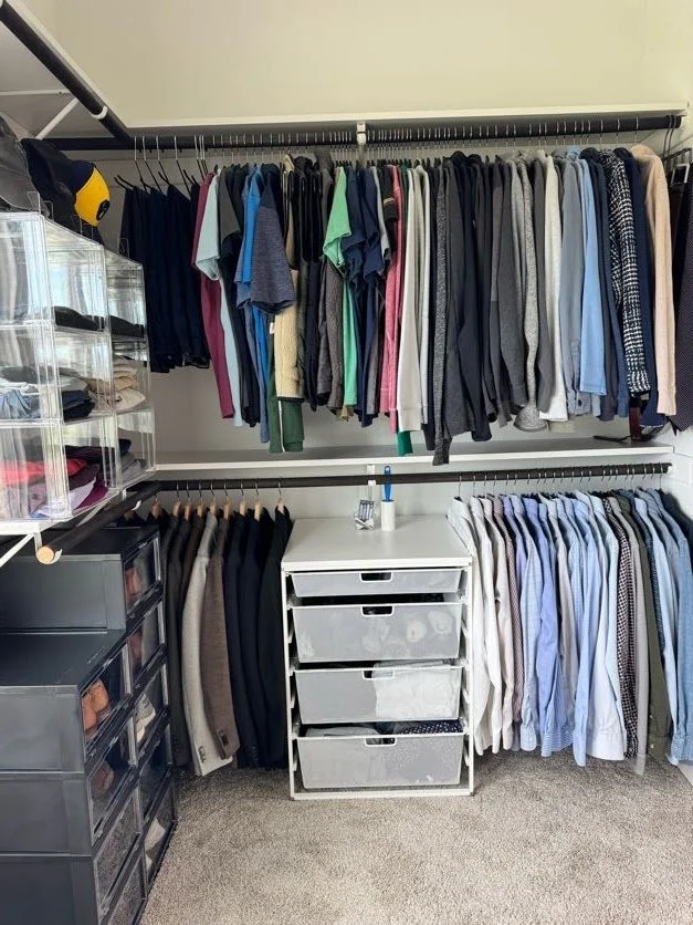Hanging men's clothing in a closet with metal drawers and black shoe boxes