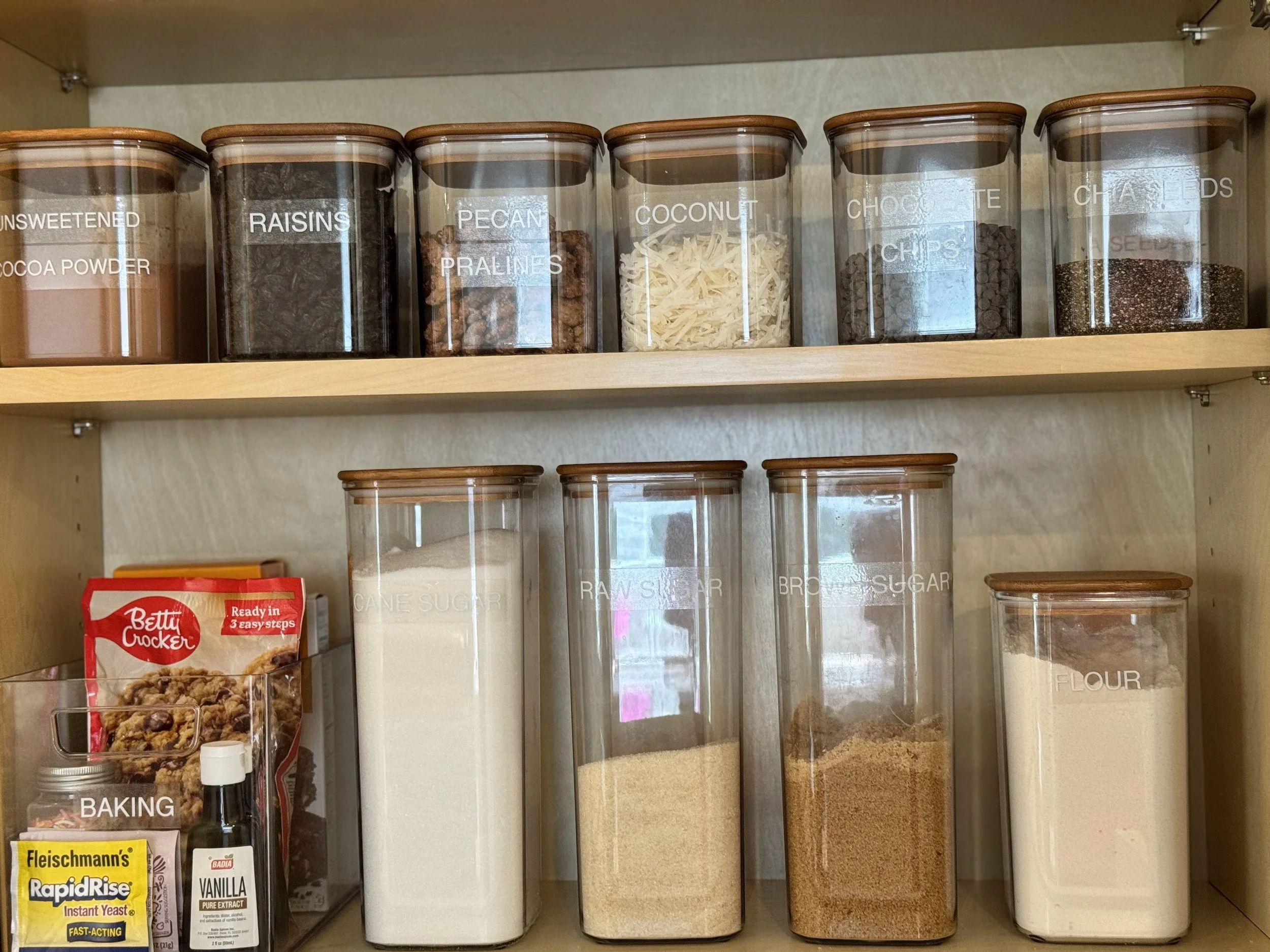 clear canisters with wooden tops and white labels for a pantry