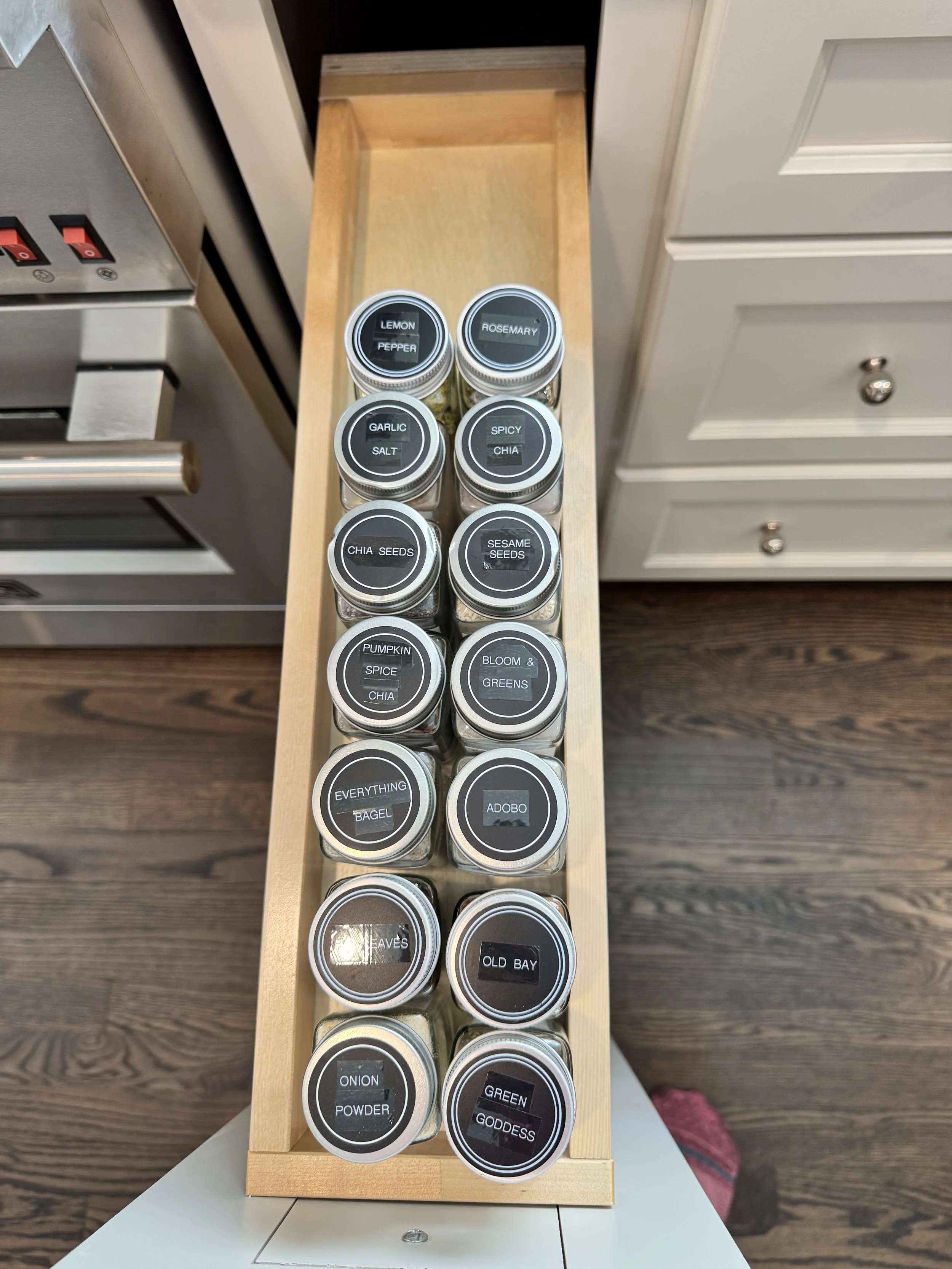 Matching spice jars with black labels in a kitchen pull out drawer