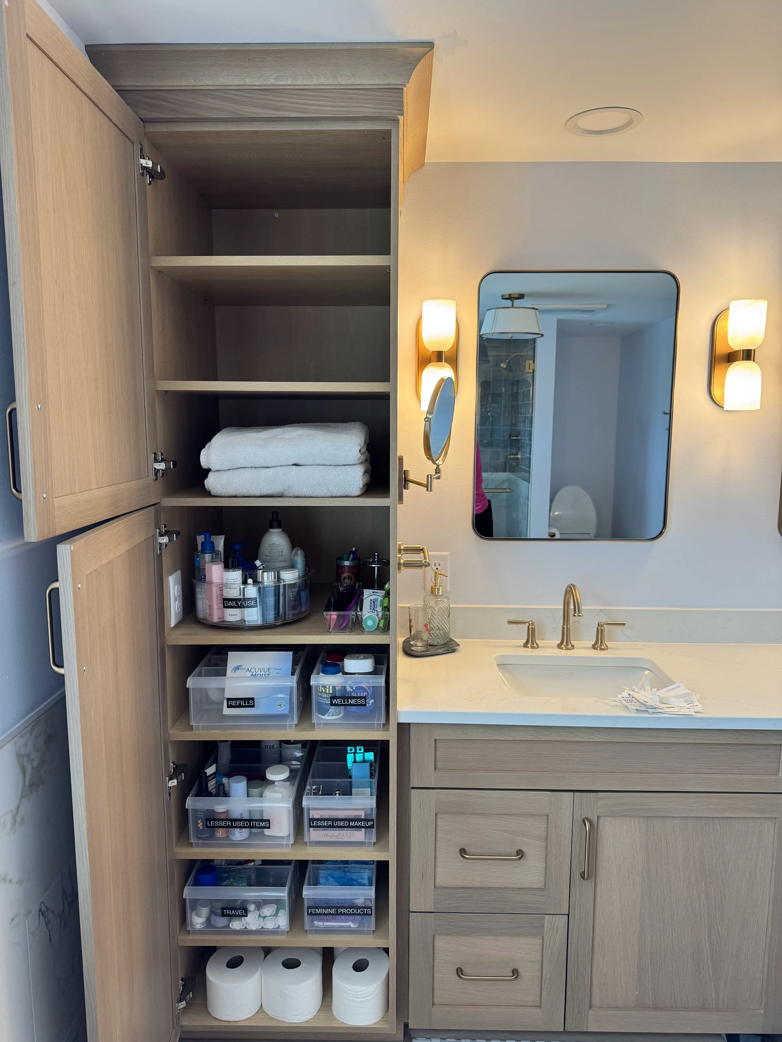 Clear containers inside a bathroom cabinet organized with labels