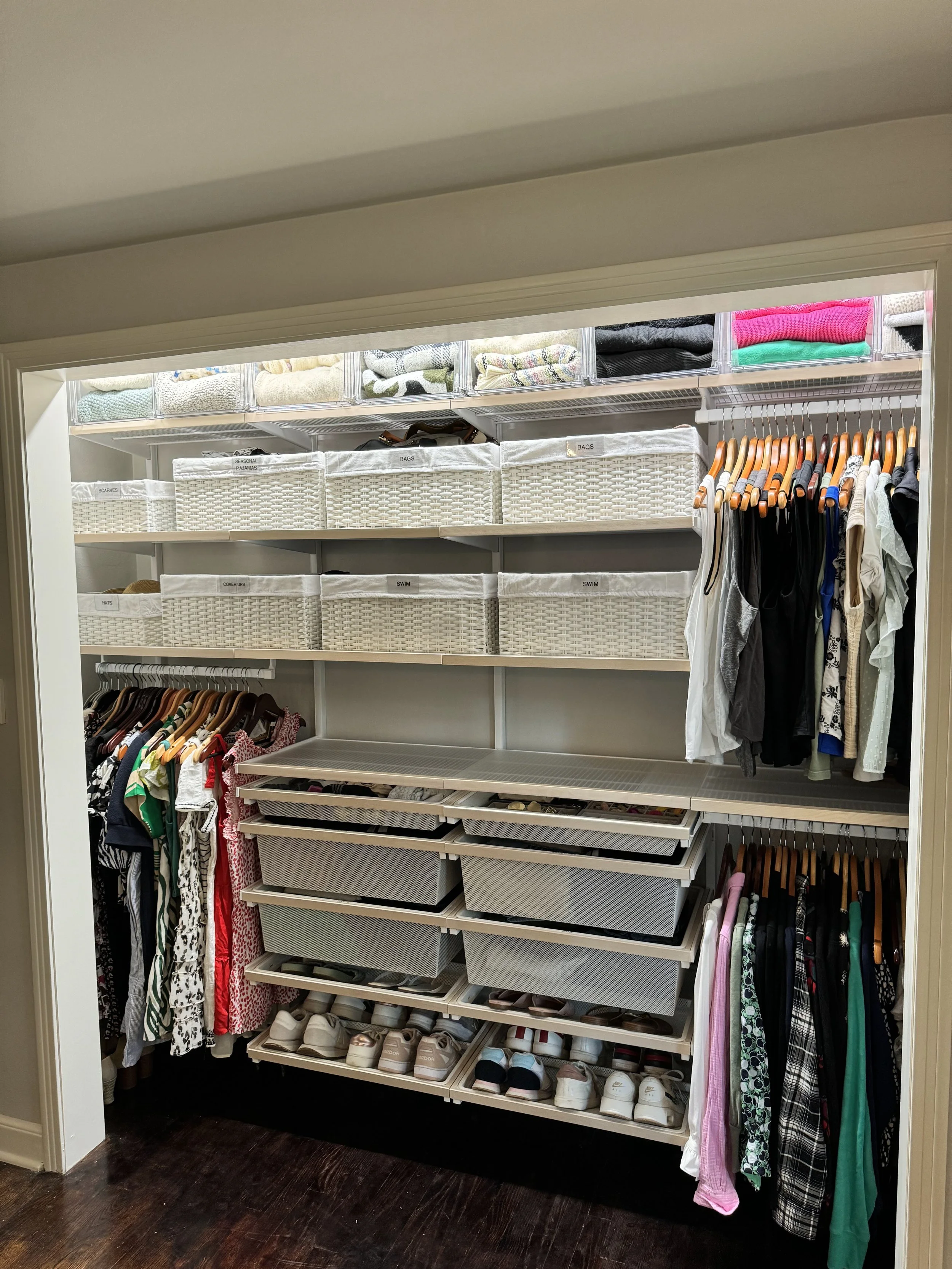 White woven baskets in a closet with metal drawers, containing shoes and folded clothes