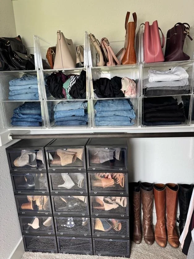 Black drop front shoe boxes in a closet with other folded clothing and hand bags organized