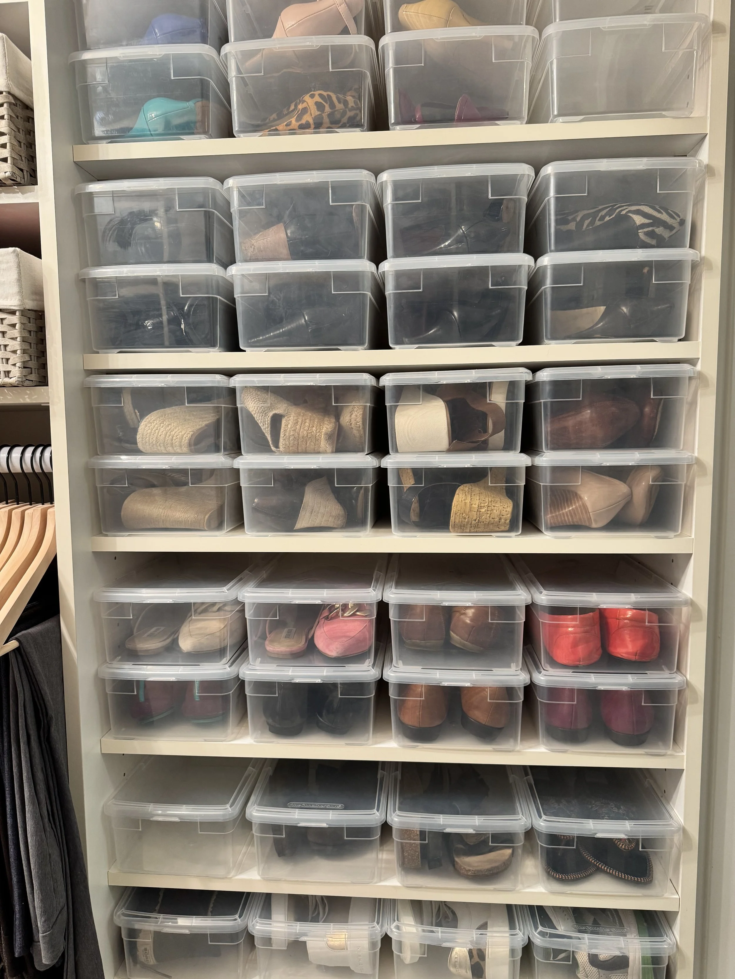 Shoes organized by clear plastic shoe boxes inside a closet