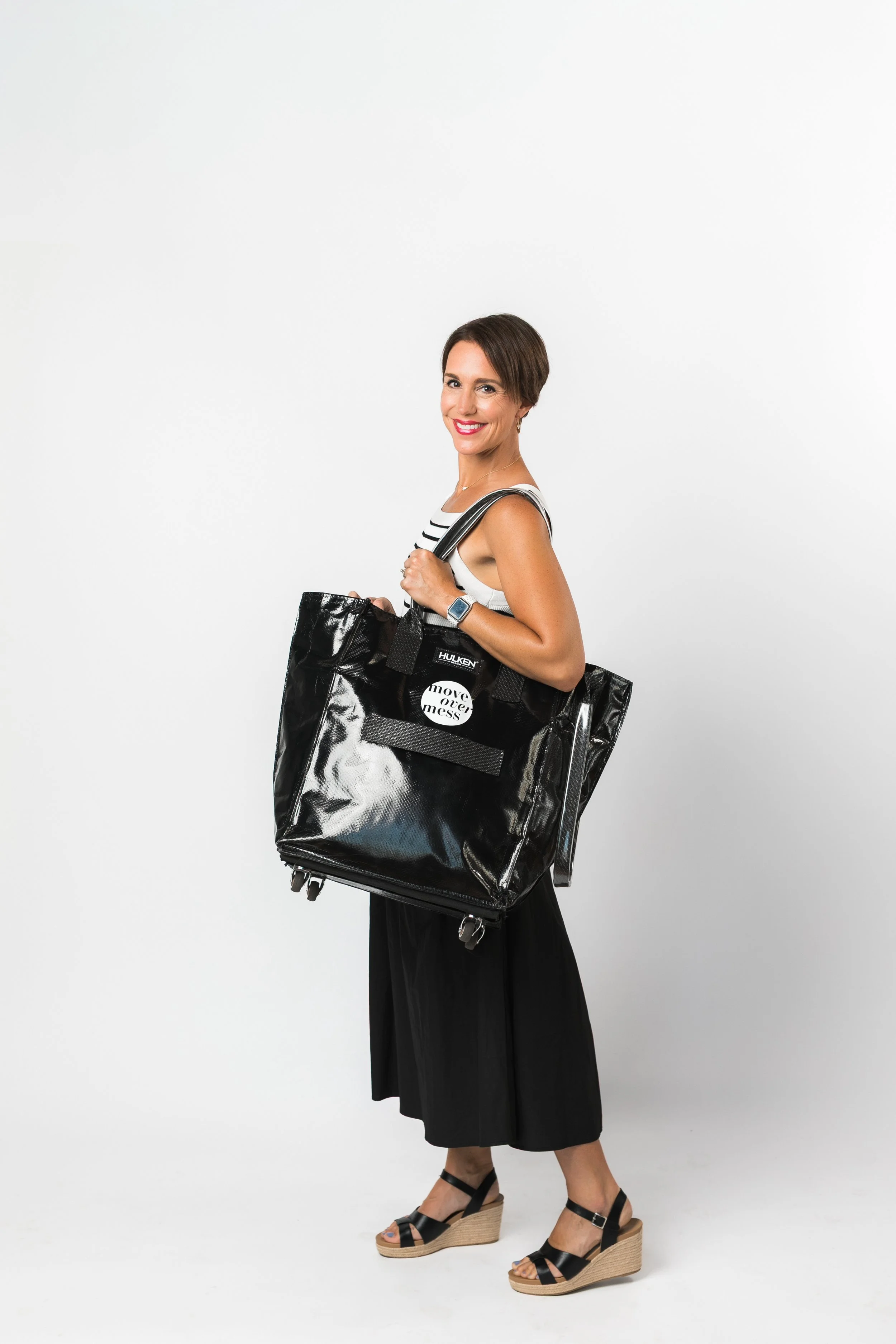 A woman in a black and white dress holding a big black bag