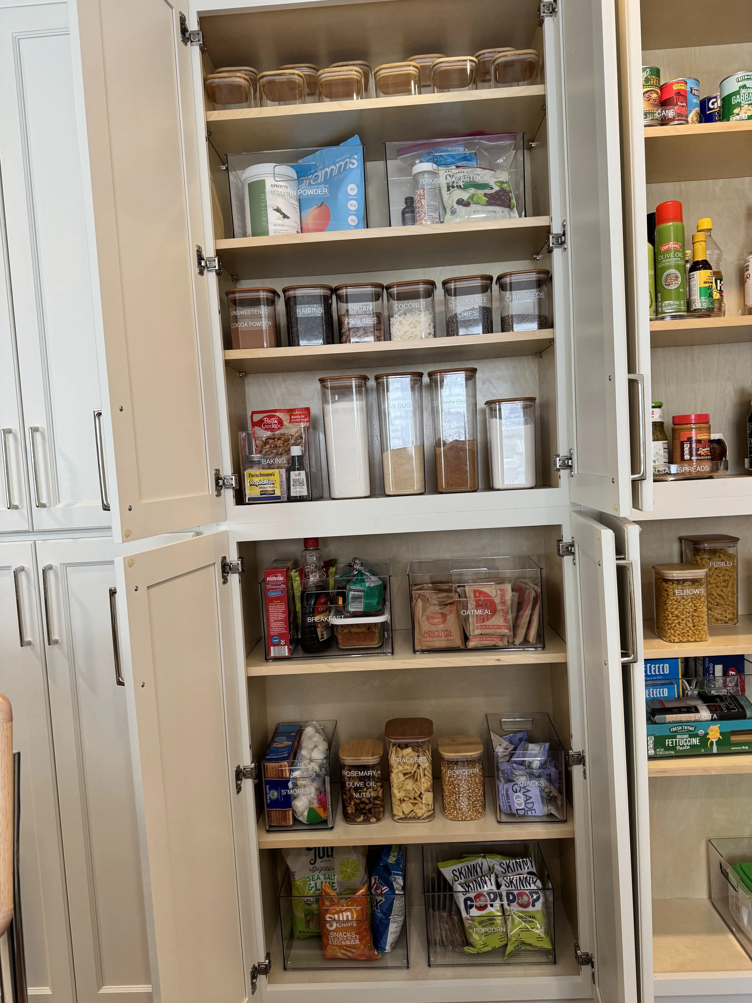 Open pantry door showing clear containers with bamboo lids holding dry goods
