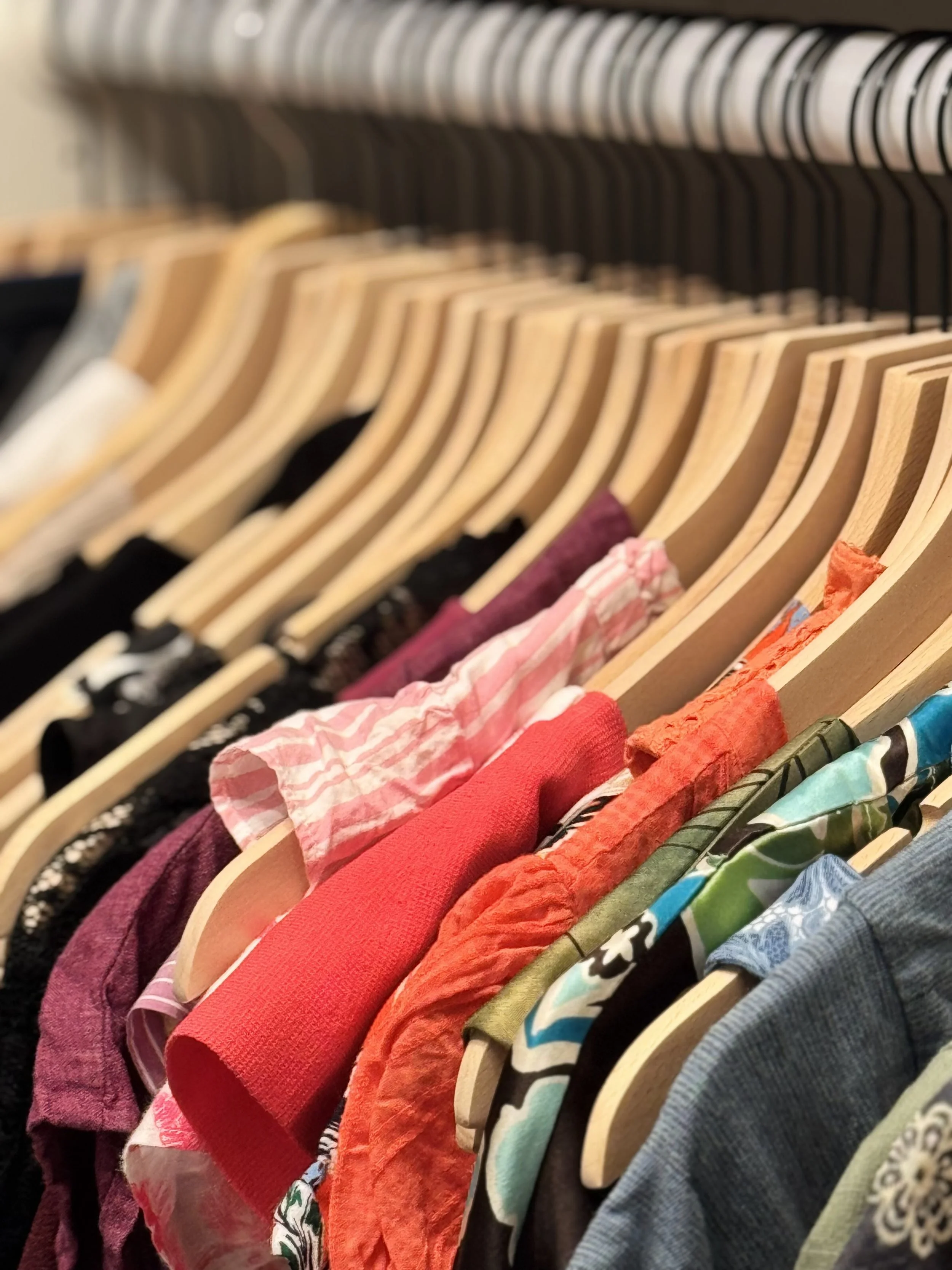 Wooden hangers and color coordinated hanging clothing in a ladies' closet