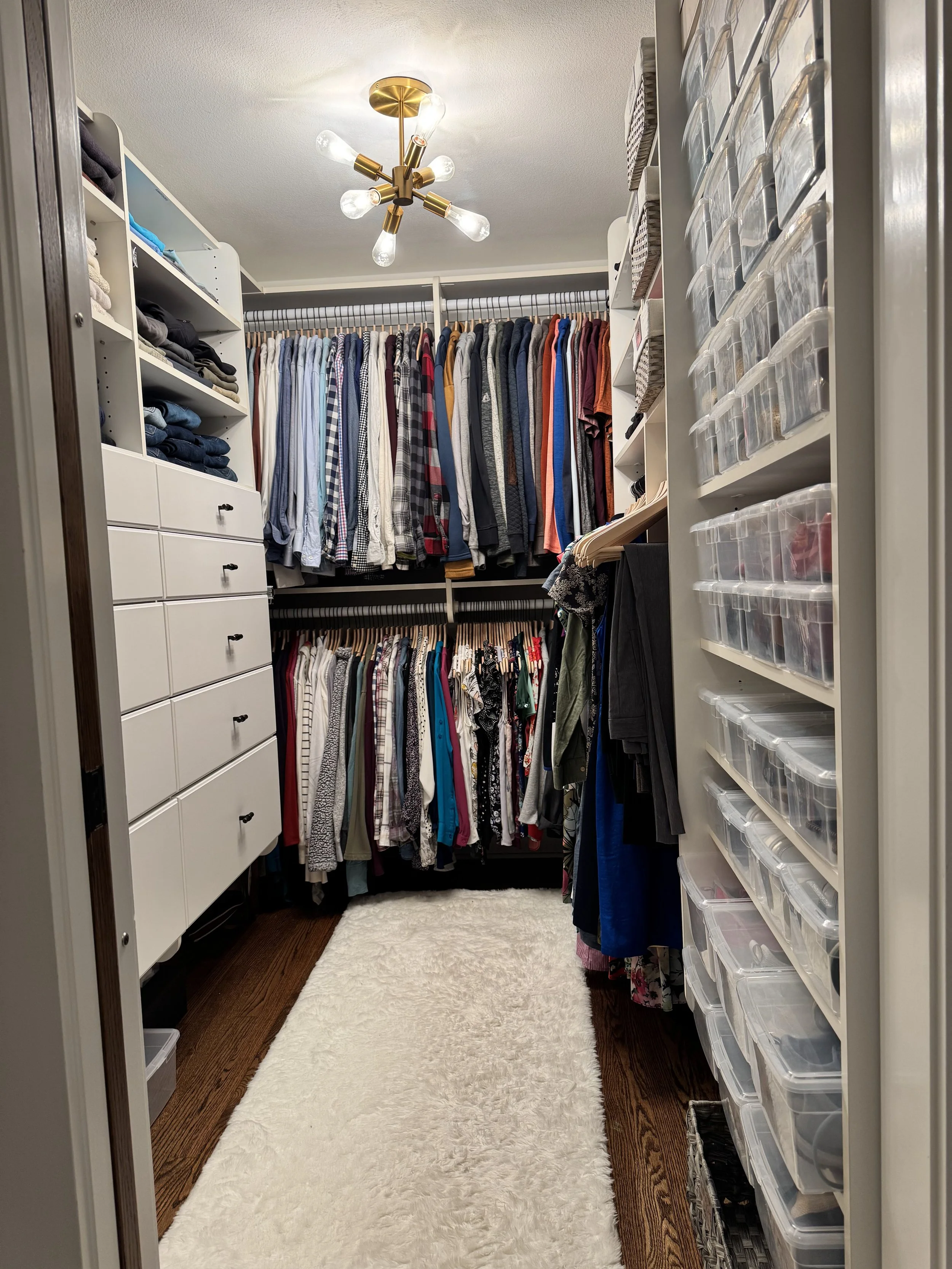 Hanging clothing and clear shoe boxes in a primary closet