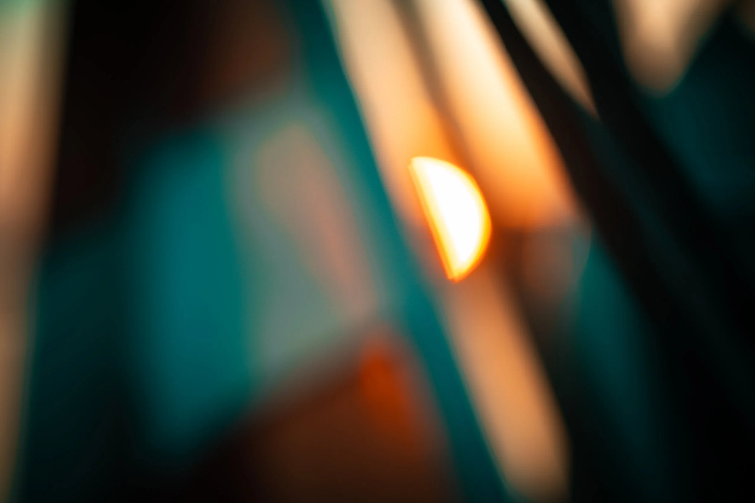 An abstract, out of focus photo with warm orange and yellow light against a darker teal and black background.