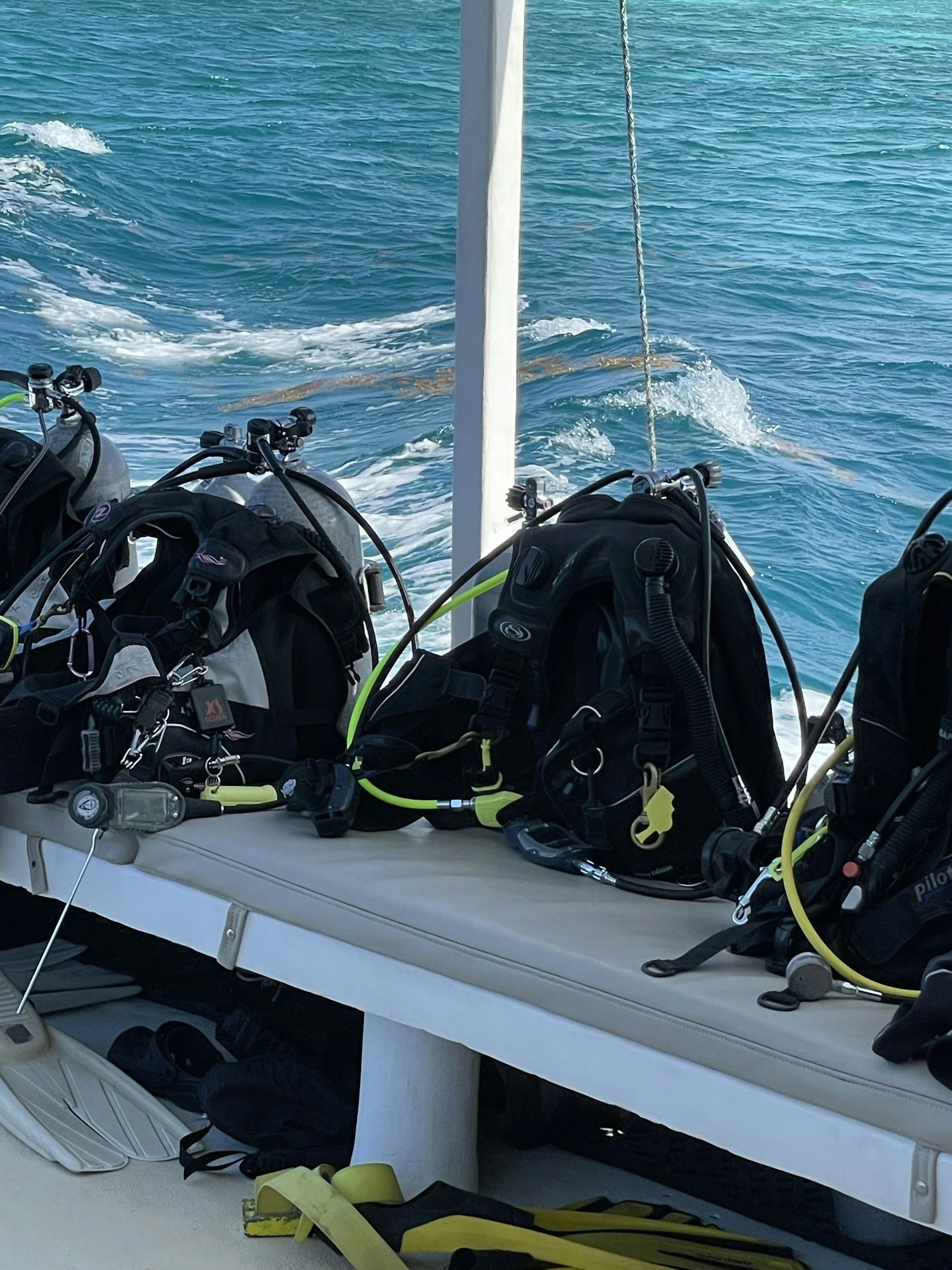 Diving equipment, including tanks and regulators, on a boat with ocean water in the background.