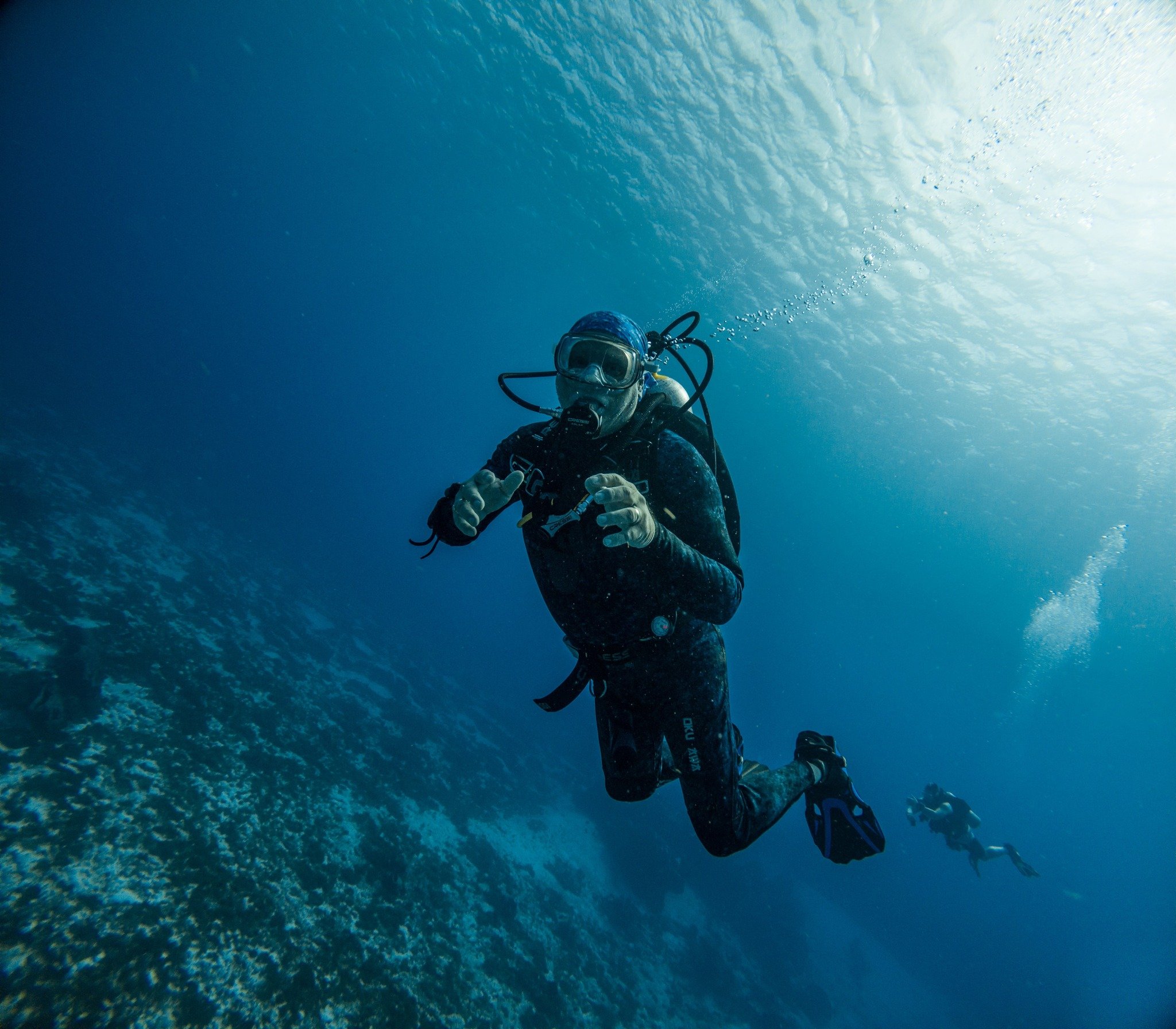 Two scuba divers swimming underwater near a coral reef.
