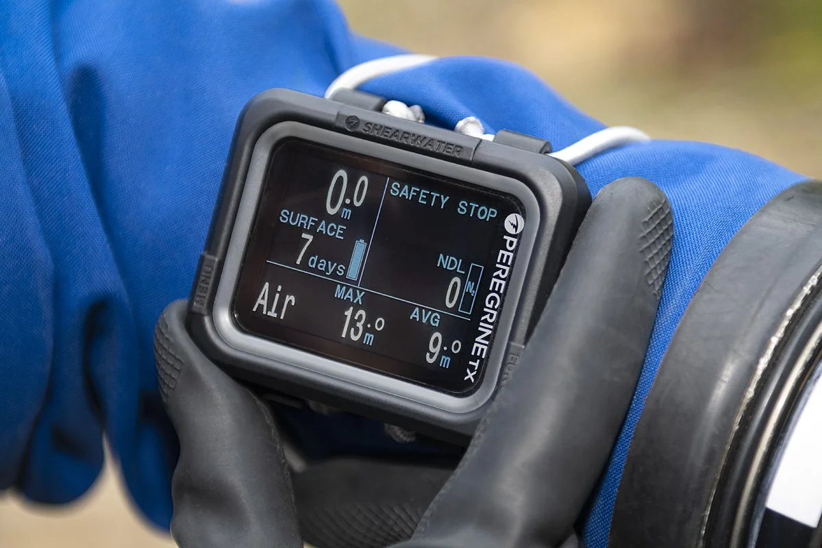 Close-up of a dive computer worn on a person's wrist, displaying dive information such as maximum depth, current depth, surface time, and air quality.