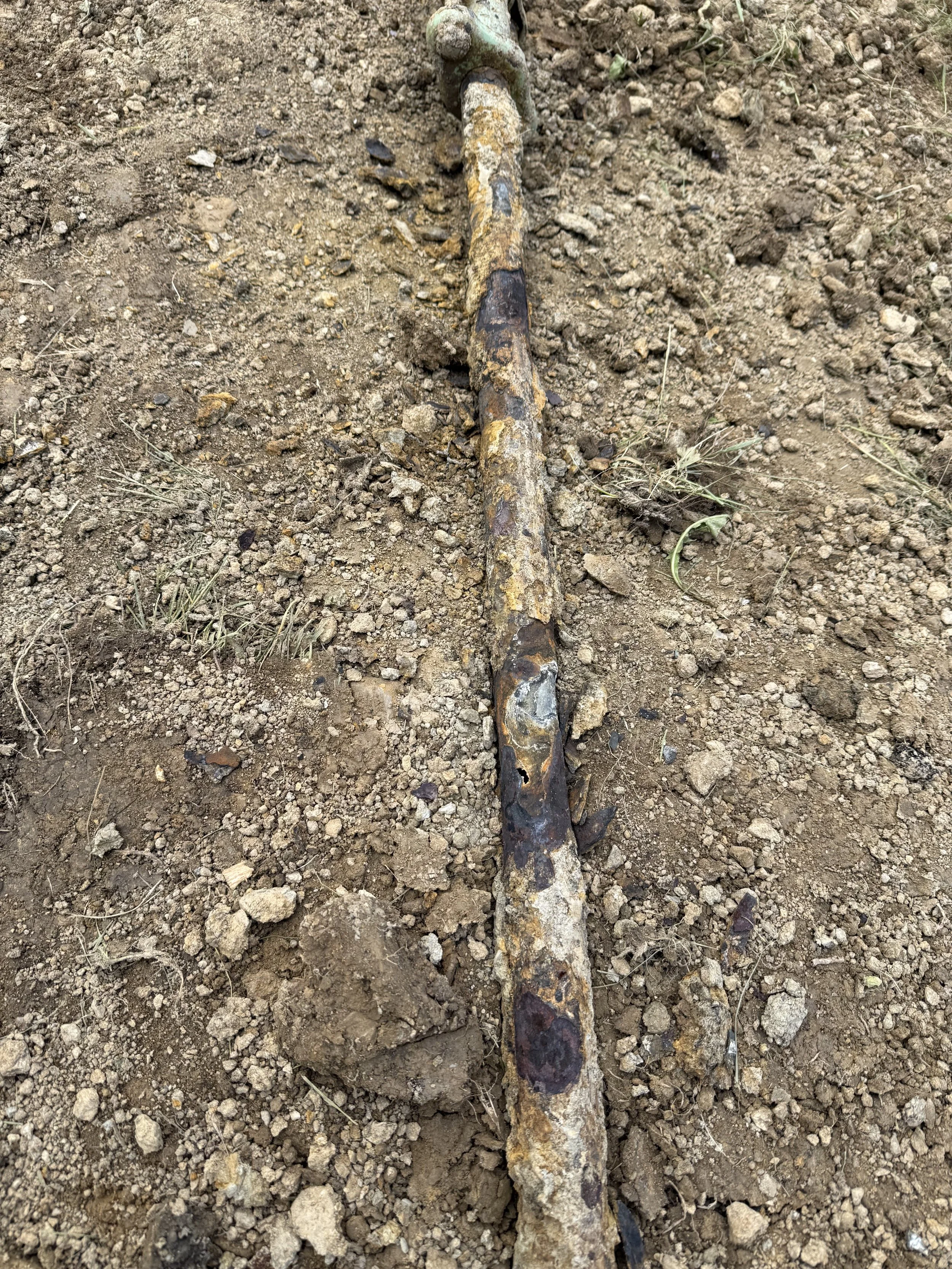 Excavated corroded underground steel gas line with a leak clamp installed in Butler, PA