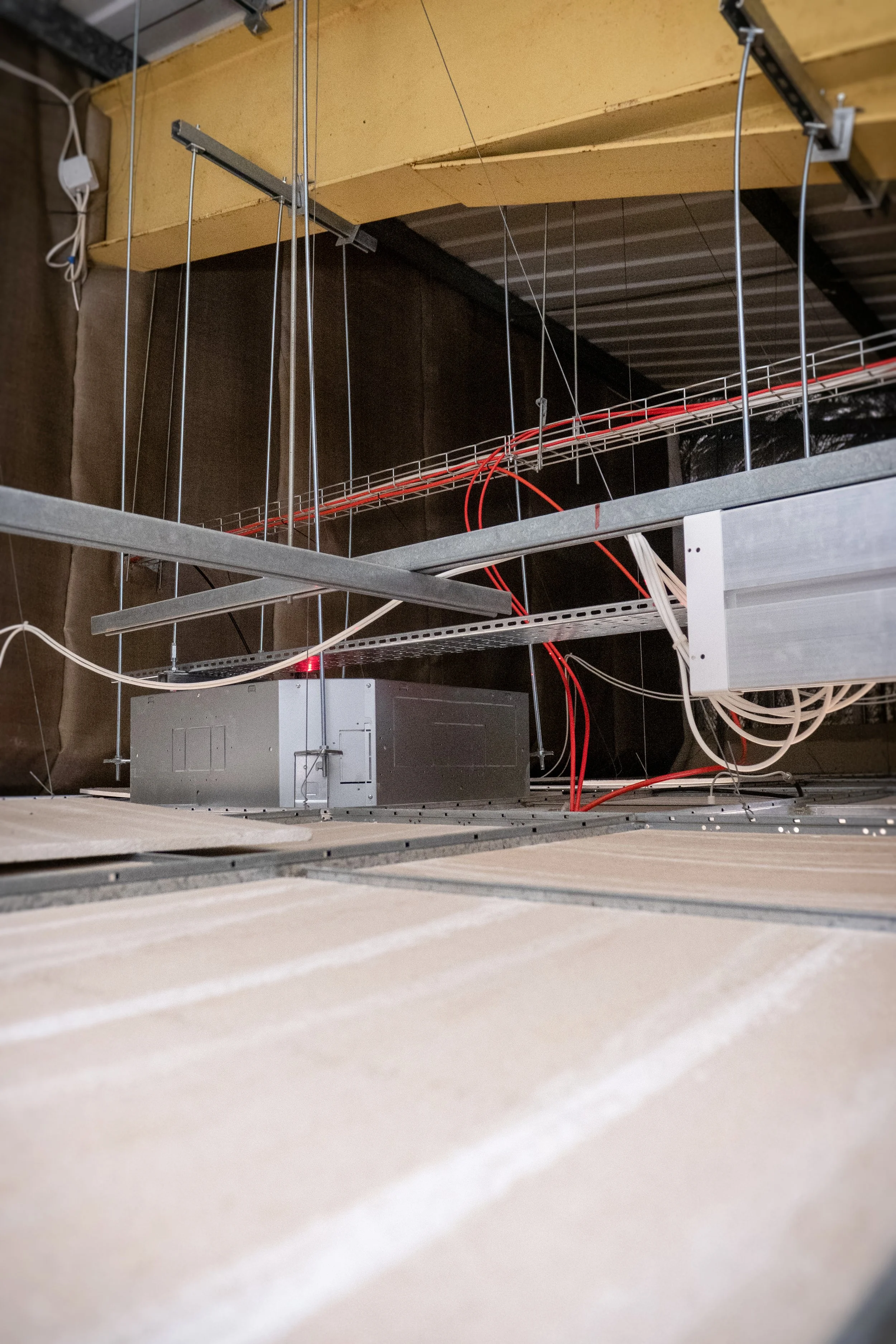 Interior of a building under construction, showing metal framing, wiring, and insulation with drywall and ceiling panels.