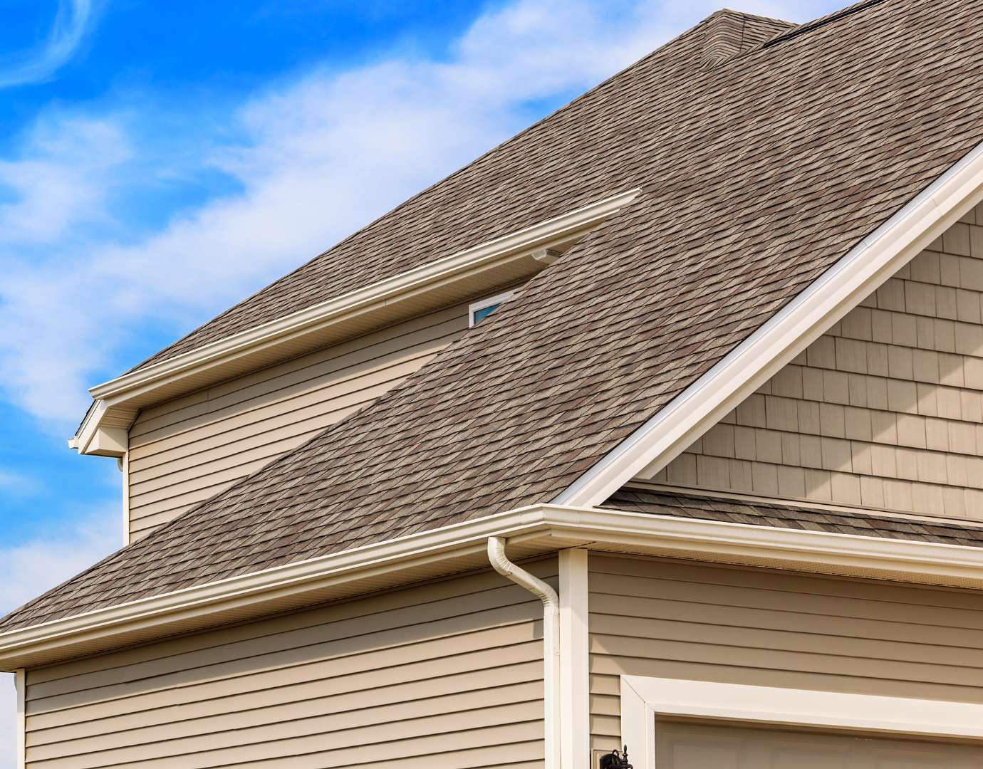 Toit en pente d'une maison beige avec bardage en vinyle, un ciel bleu en arrière-plan| Projet résidentiel | Stefix Construction Inc.
