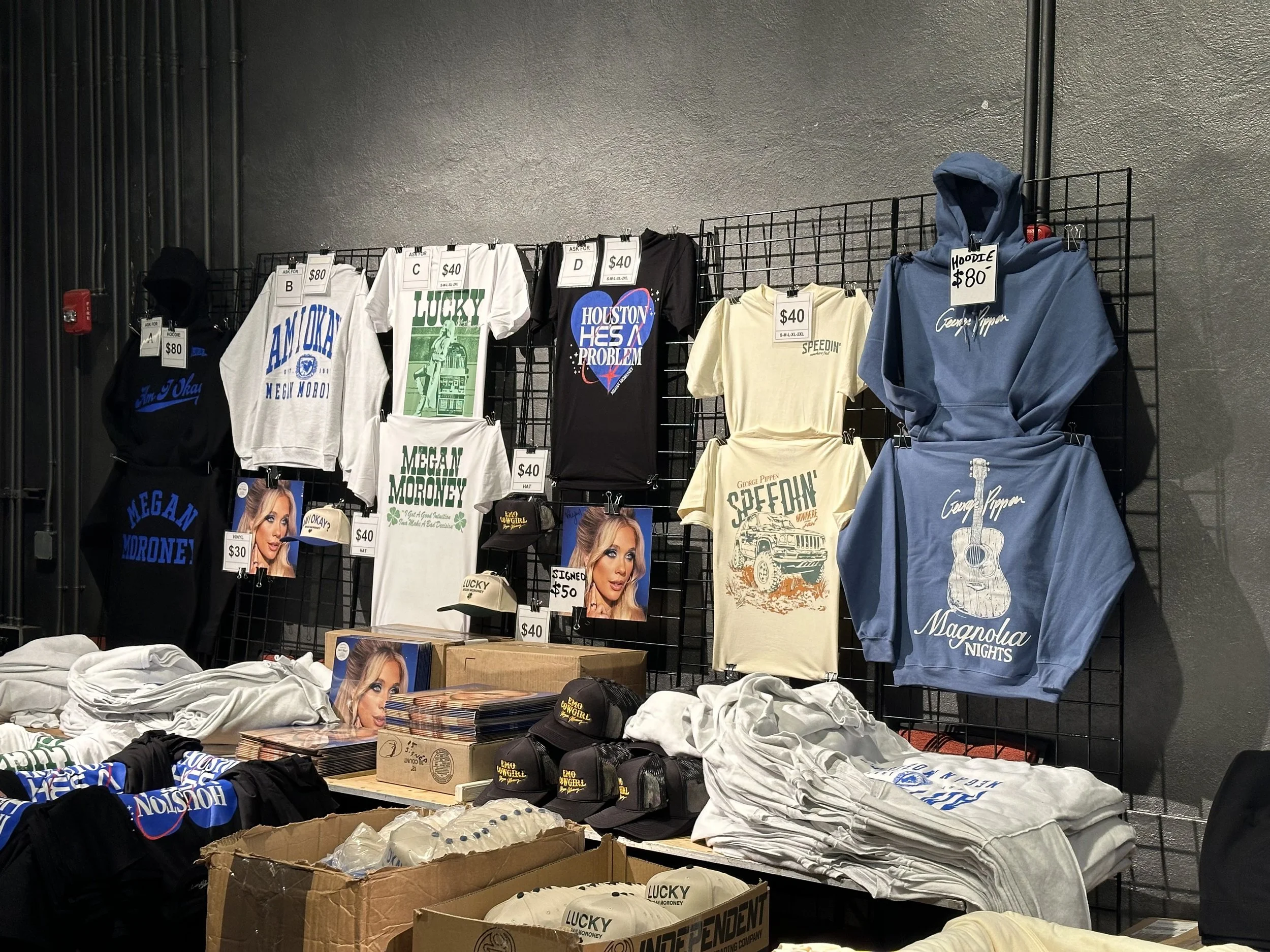 Touring merch booth setup showing multiple artist lineups.