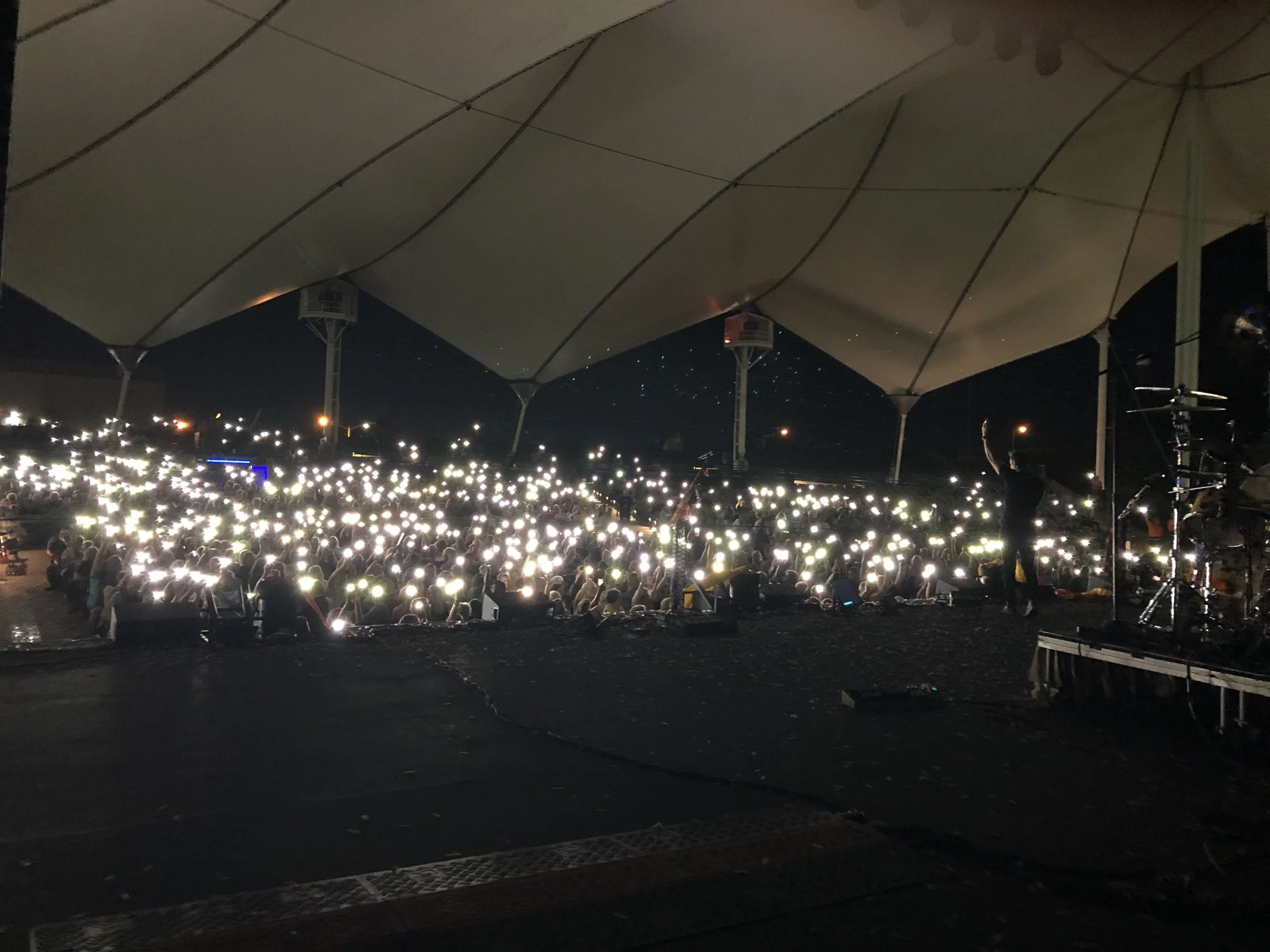 Artist cheering with fans as the shine their flashlights under canopy of amphitheater