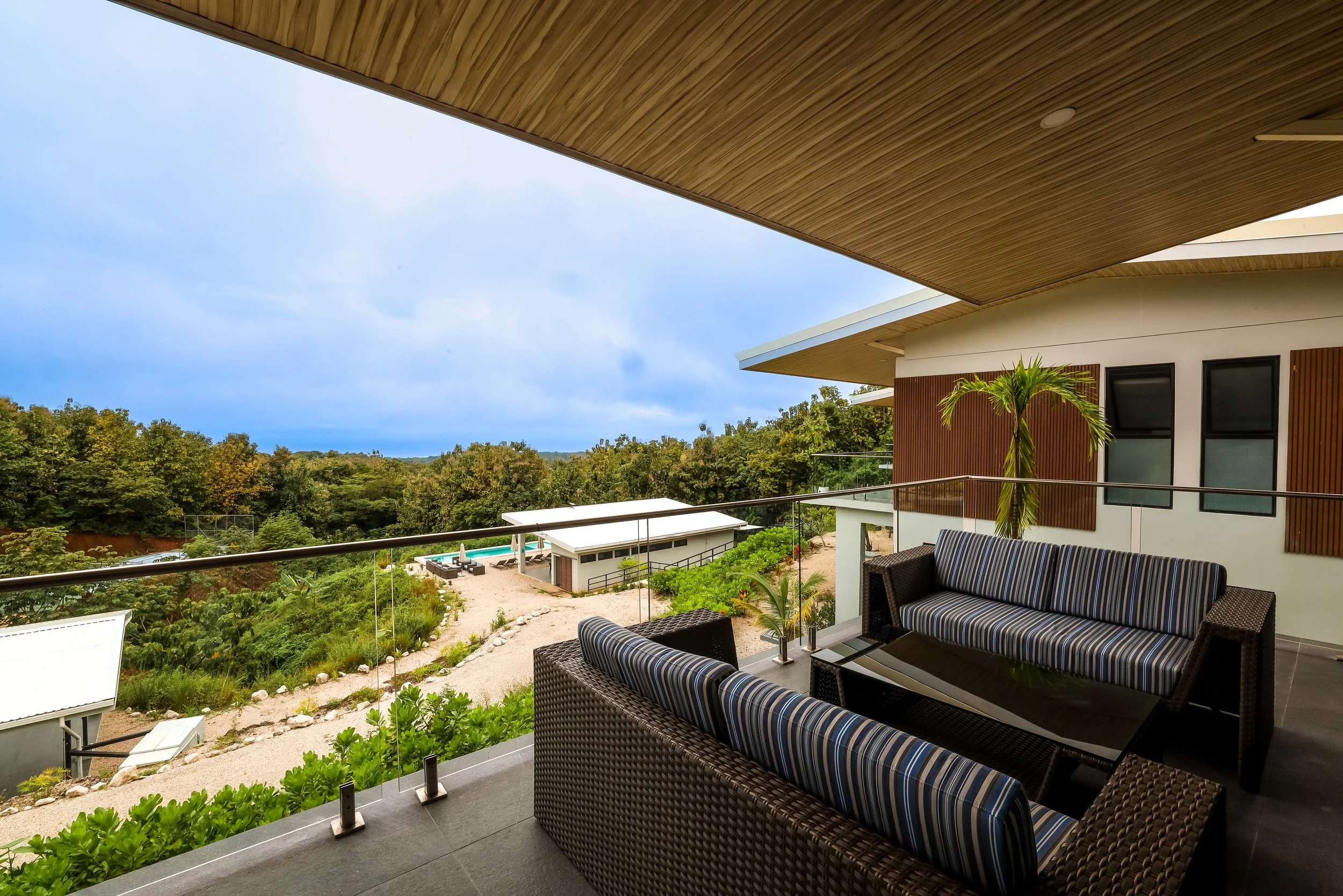 Balcony view of a modern villa in Marbella, Guanacaste, featuring outdoor seating and views of the lush tropical landscape.
