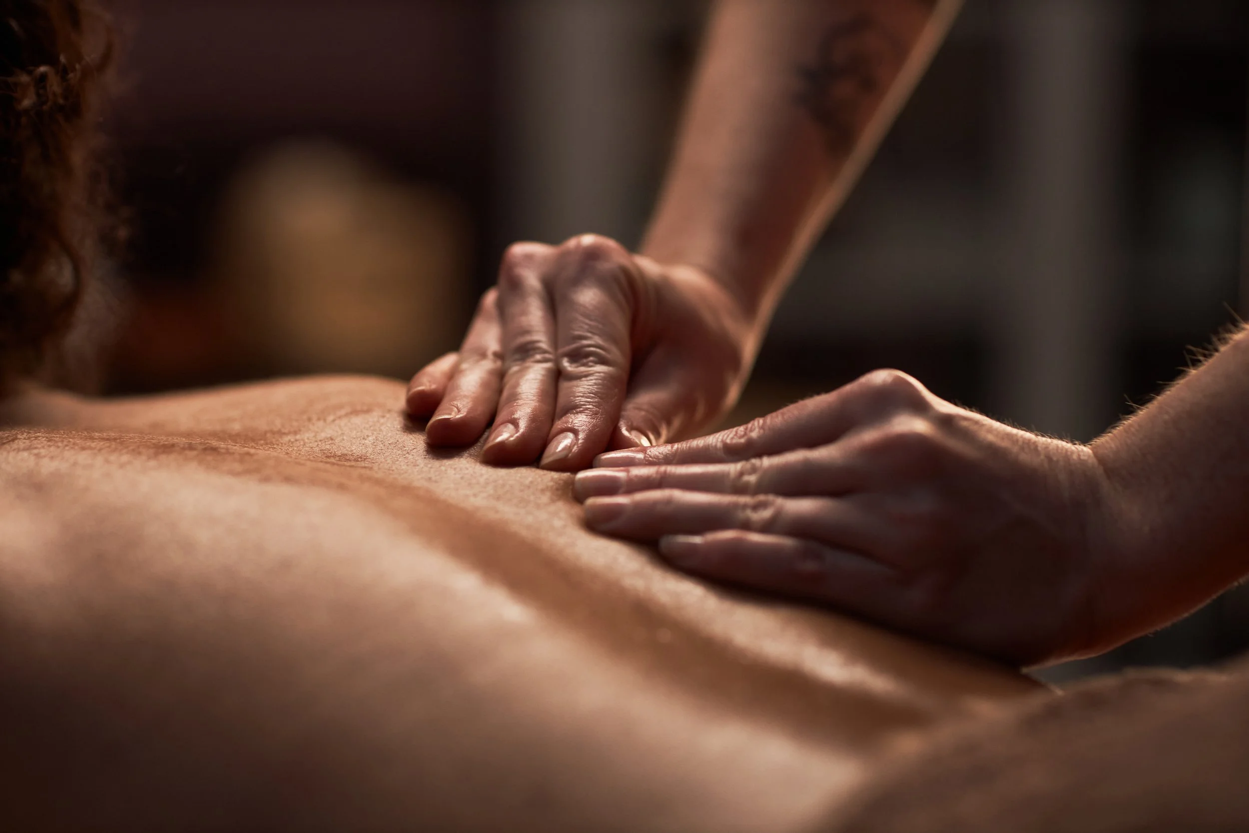 A person giving a massage on a person's back, focusing on hands and back muscles.