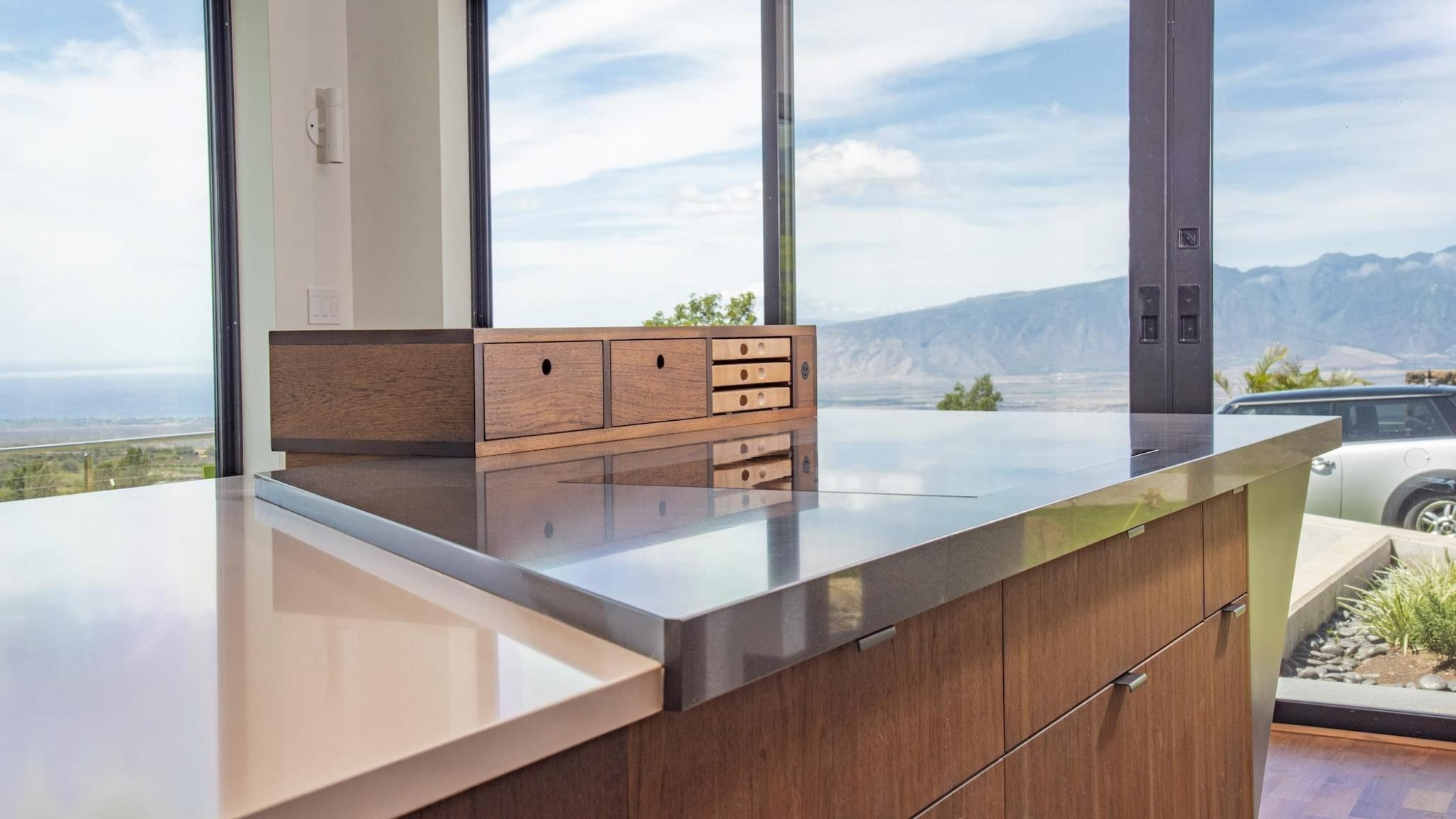 Modern hitchen with a view of a stainless counter and a large window overlooking maui, designed by Marshall Design Studio