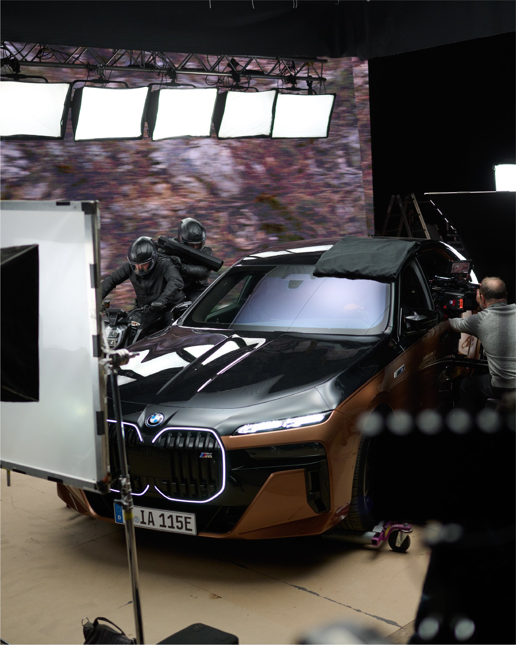 Film set with a BMW i7 car, motorcycle, and filming equipment