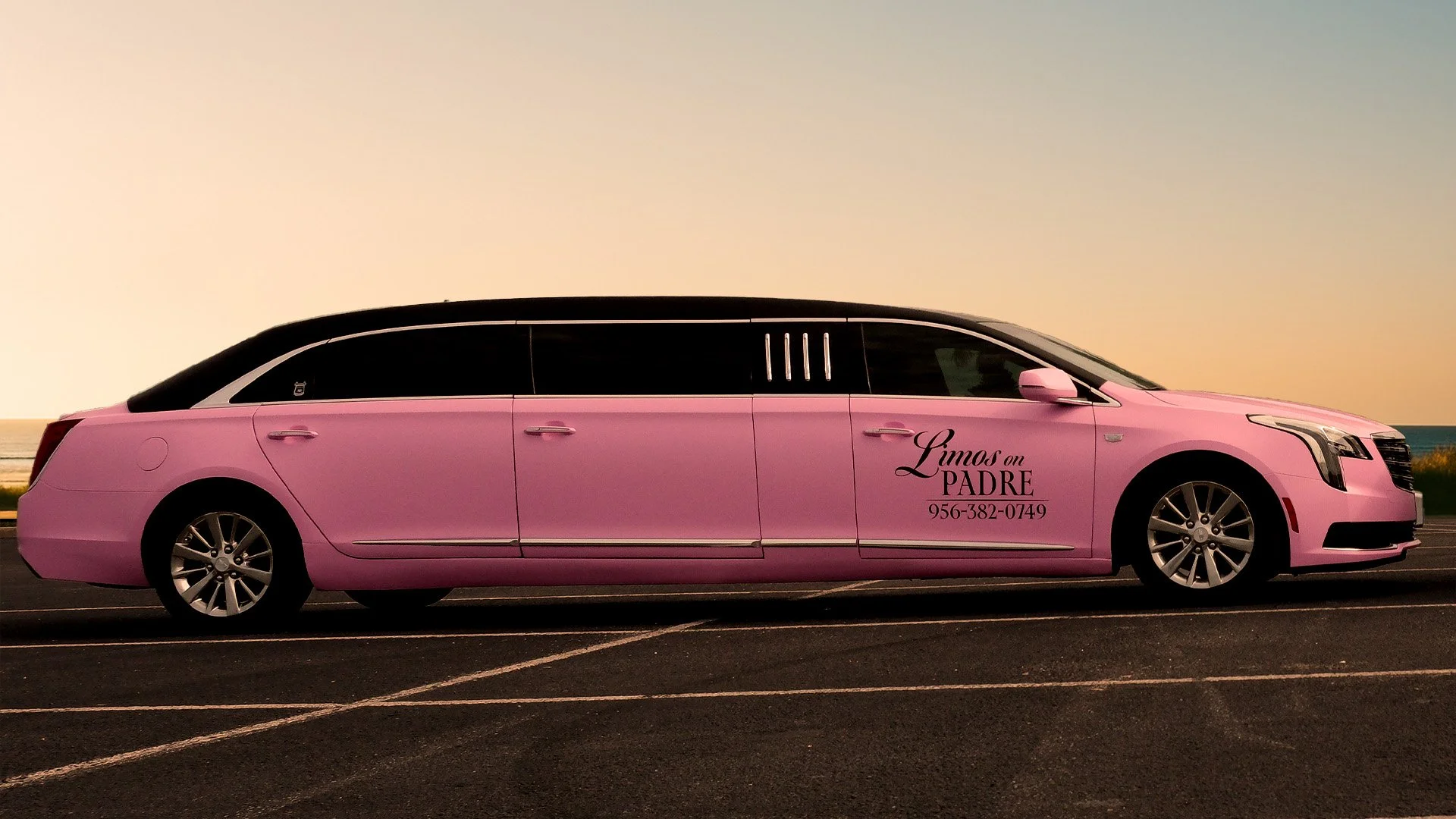 Pink limousine parked on a road near the beach during sunset, with text advertising a chauffeured limo service for 'Limos on PADRE' and a phone number.