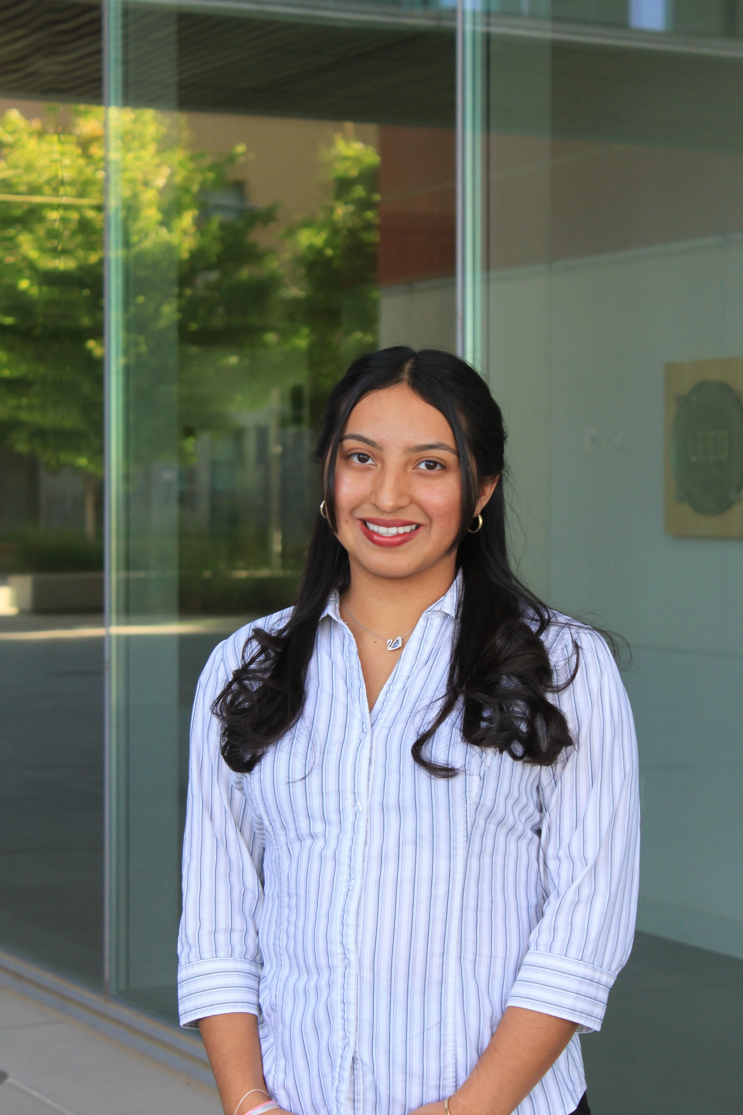 A person in a business suit standing in front of a glass building.