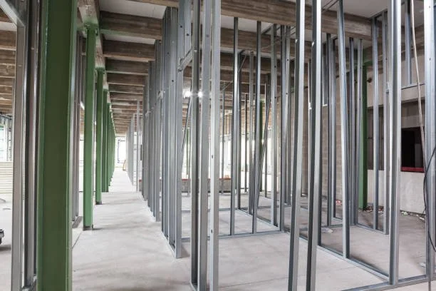 Interior of a building under construction with metal framing and green support beams.