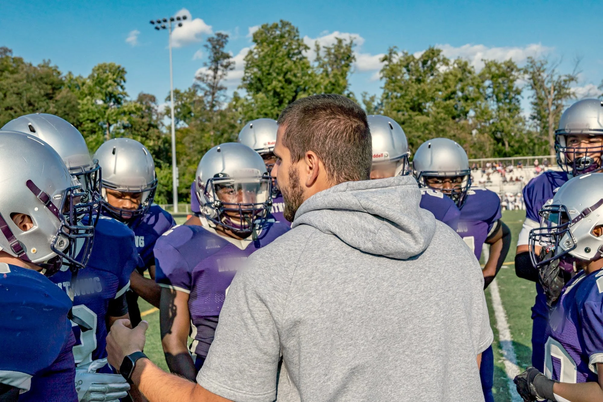Coach huddling with a youth football team