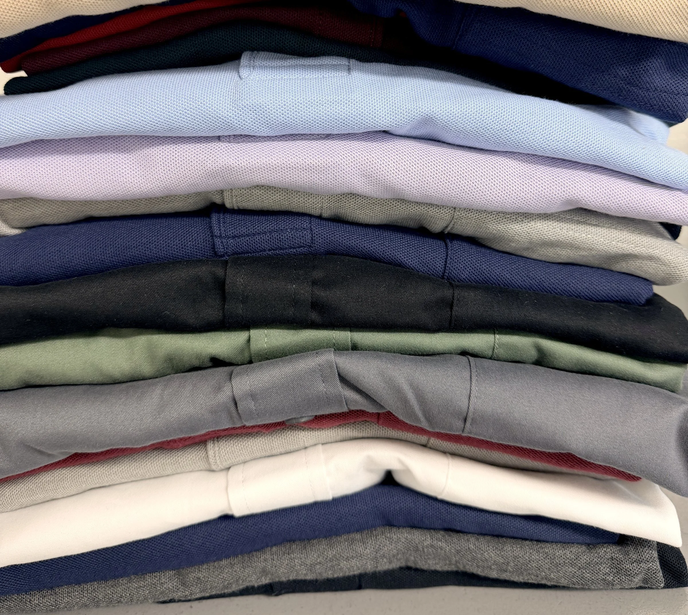 Stack of team polos in a range of colors at Uniforms & More