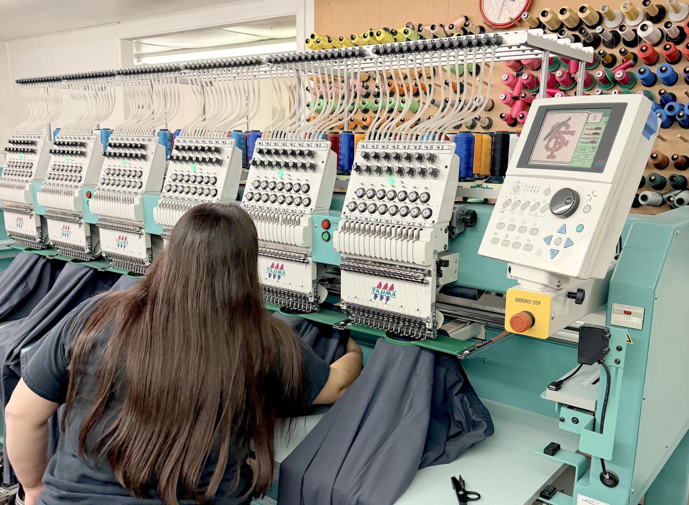 Uniforms & More team member running a multi-head embroidery machine in the Albuquerque shop