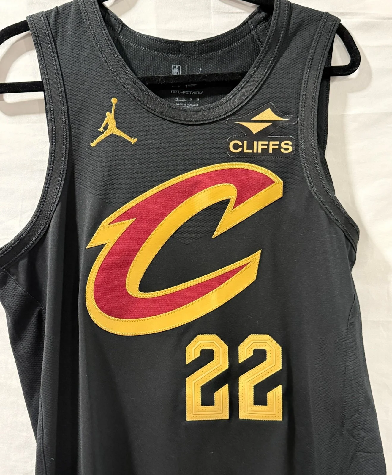 A black sports jersey with the Cleveland Cavaliers logo, a large red and yellow letter 'C', the number 22, and two patches that say 'Cliffs' and feature the Jumpman logo.