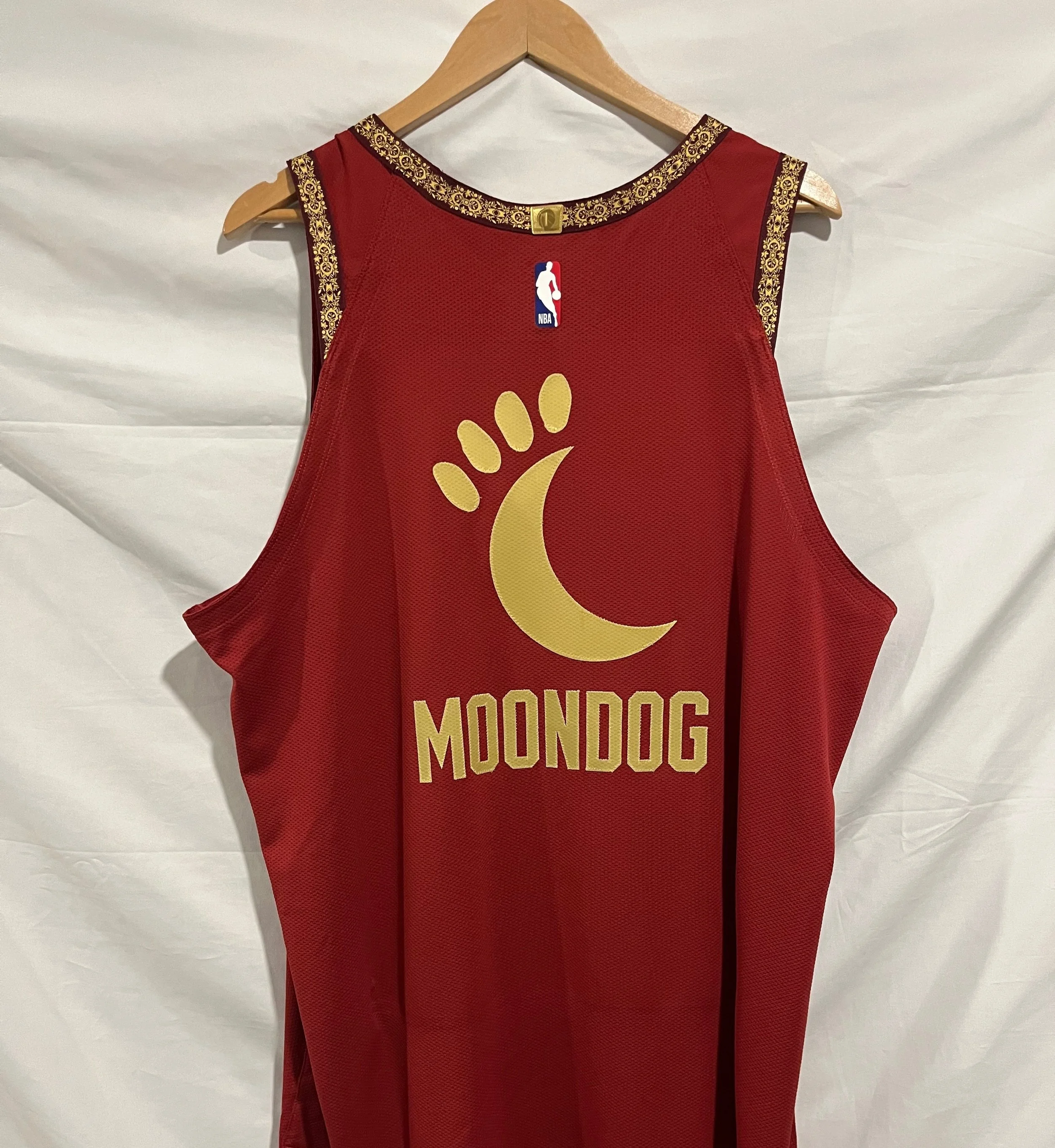 Cleveland Cavaliers City style basketball jersey for Mascot Moondog  with gold trim and logo, hanging on a wooden hanger against a white background.