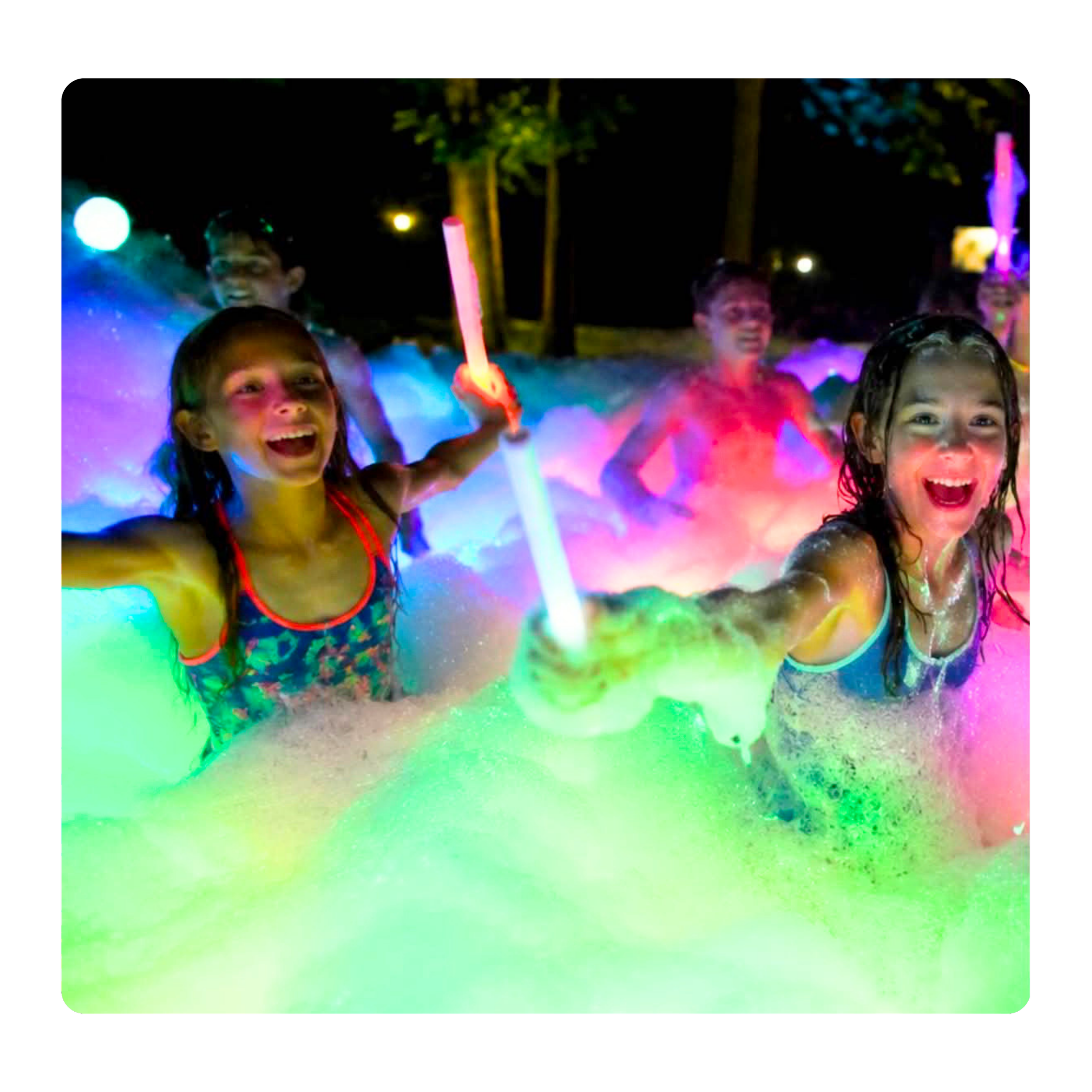 Children playing with colorful glow sticks in a dark outdoor setting, smiling and enjoying the night