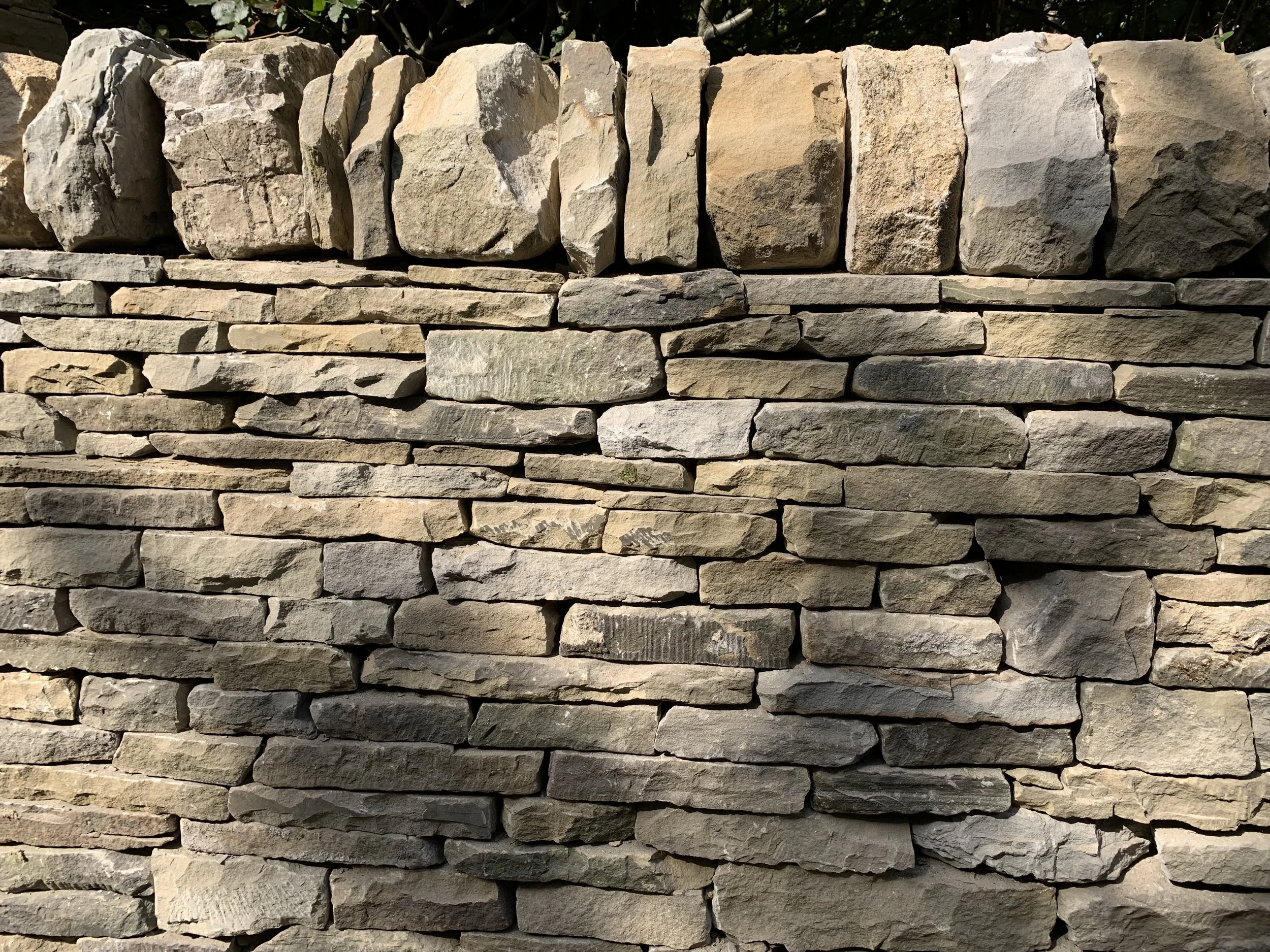 Close-up of a dry stone wall with uneven, natural-colored stones.