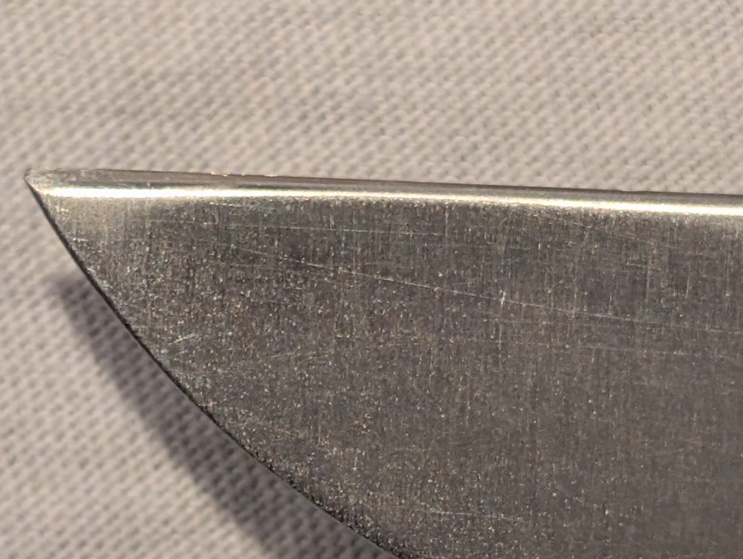 Close-up of a knife blade edge on a textured surface