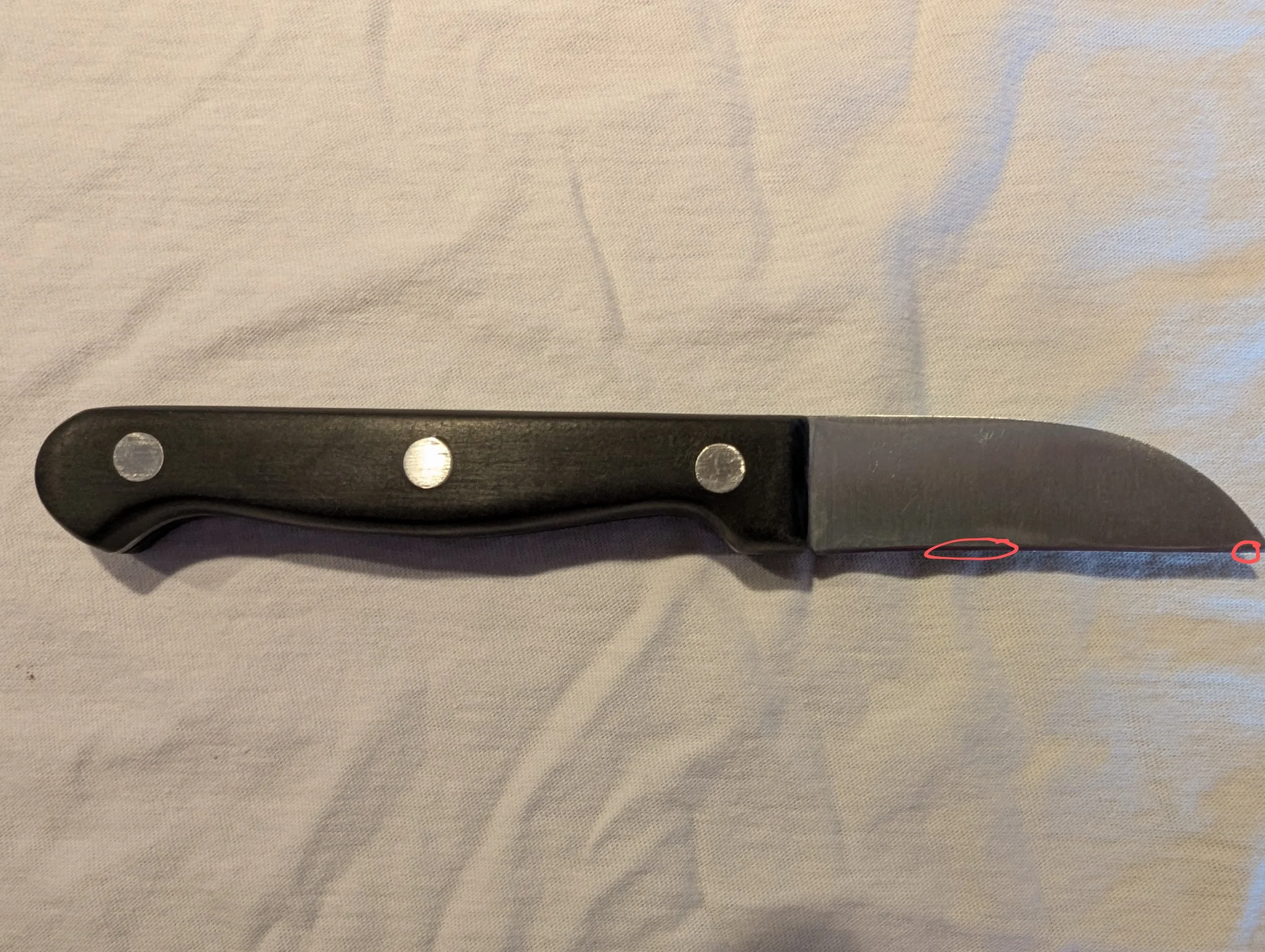 paring knife with black handle on white surface.
