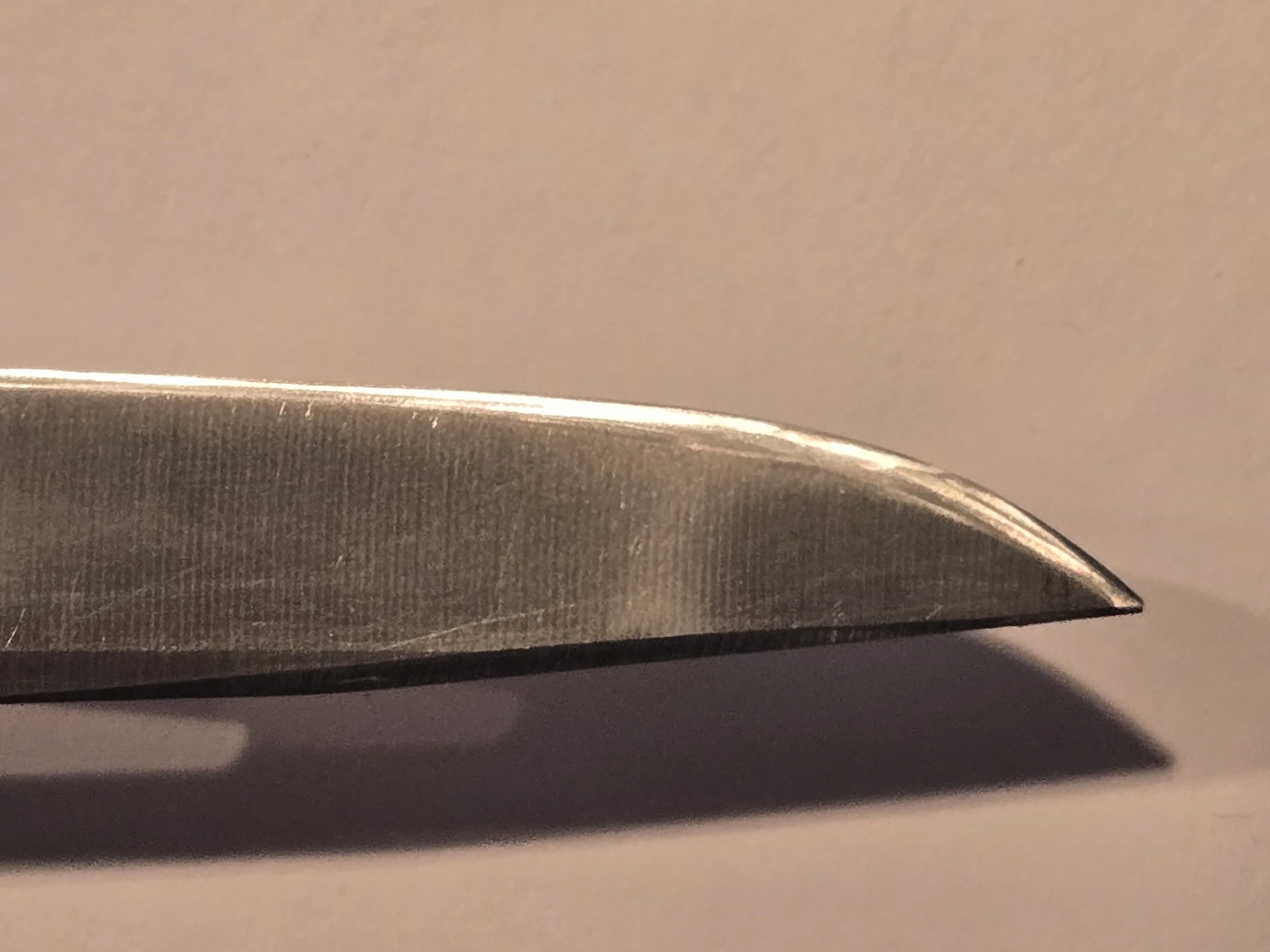 Knife blade close-up with shadow on a neutral background